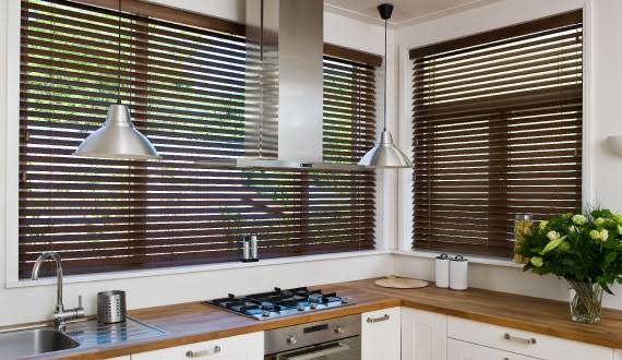 Kitchen with wooden blinds, stainless steel hood, and countertop.