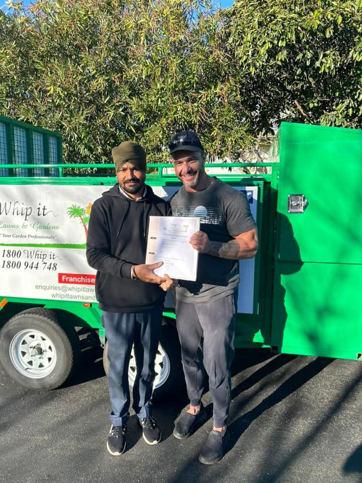 Two men are standing next to each other in front of a green truck holding a certificate.