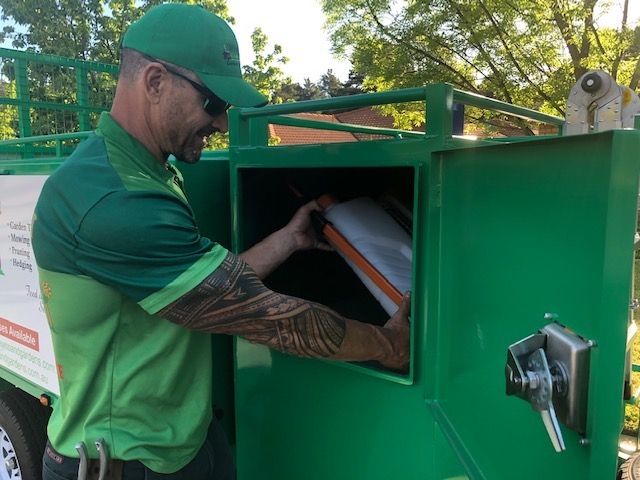 A man in a green shirt is working on a green truck