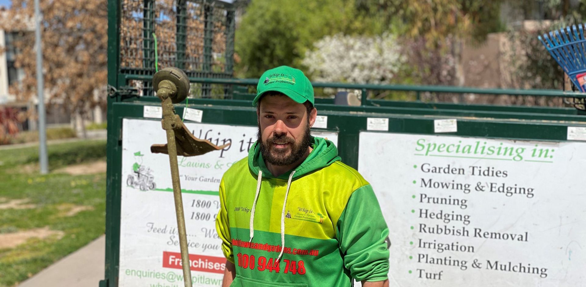 A man is standing in front of a sign holding a broom.