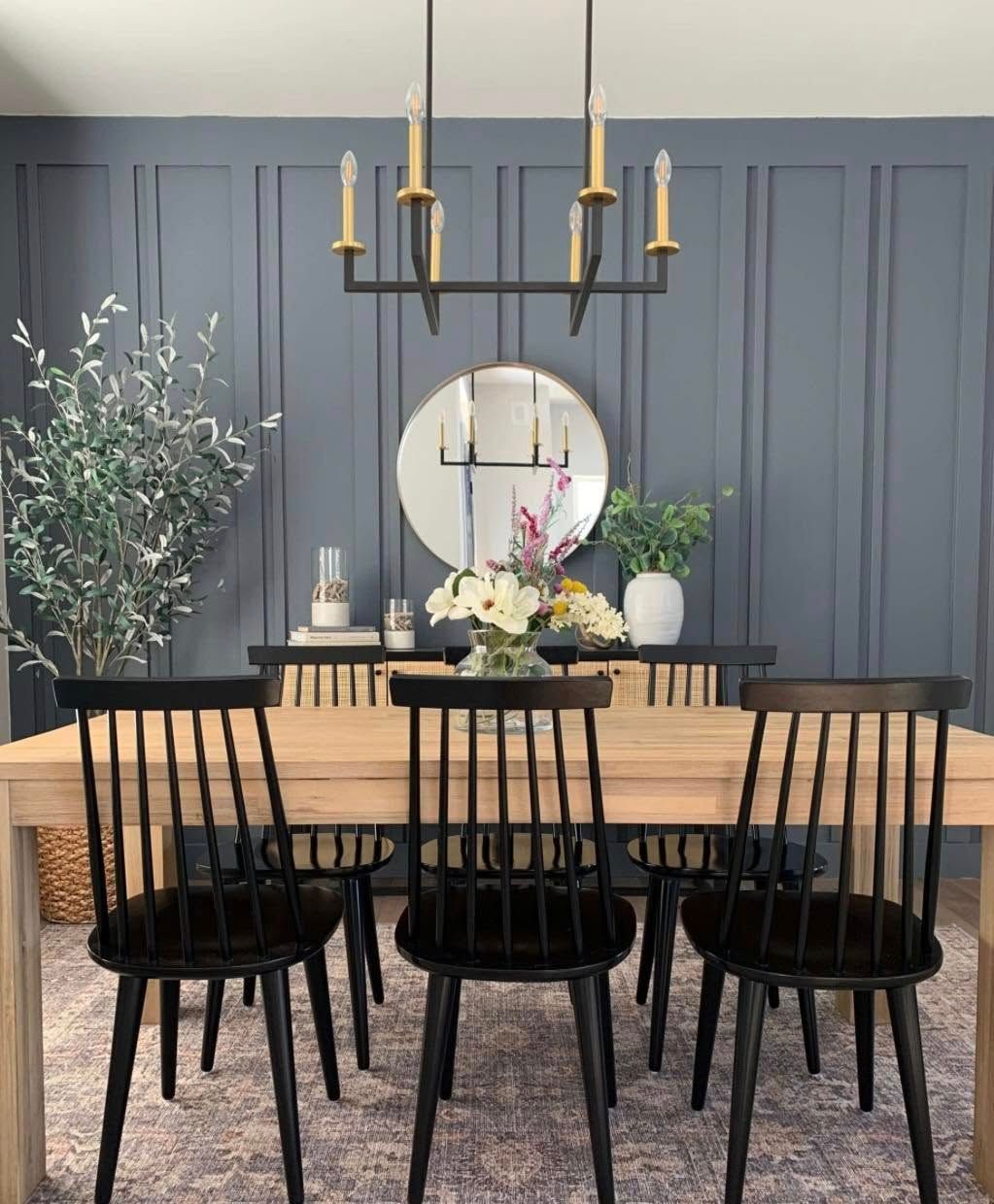 Dining room with black chairs, light wood table, and blue panel wall.