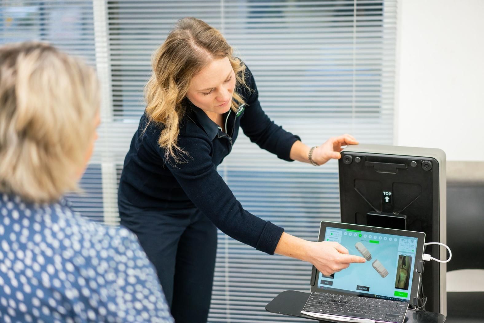 A Woman Points at a Laptop Screen Displaying Medical Imagery — Alice Springs Podiatry in Ciccone, NT