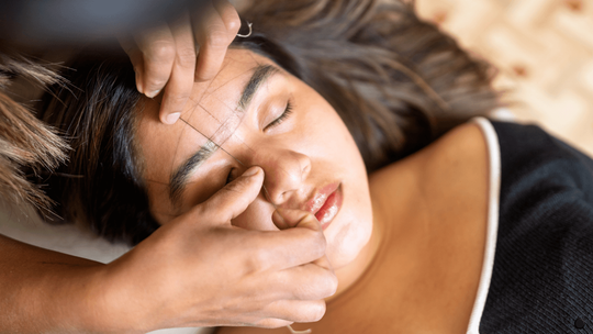 microblading artist mapping woman's eyebrows.