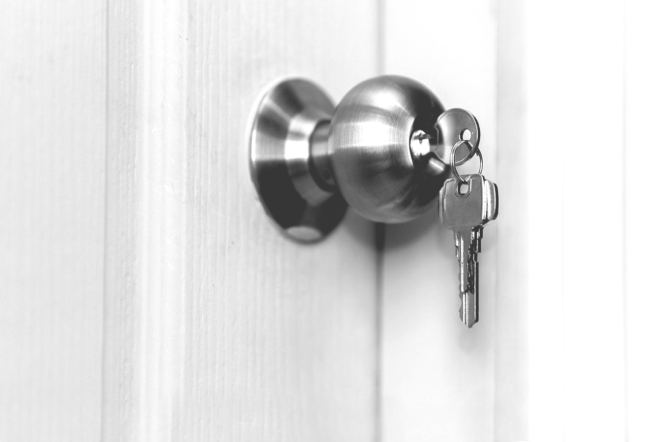 Door knob with keys inserted, attached to a white door.