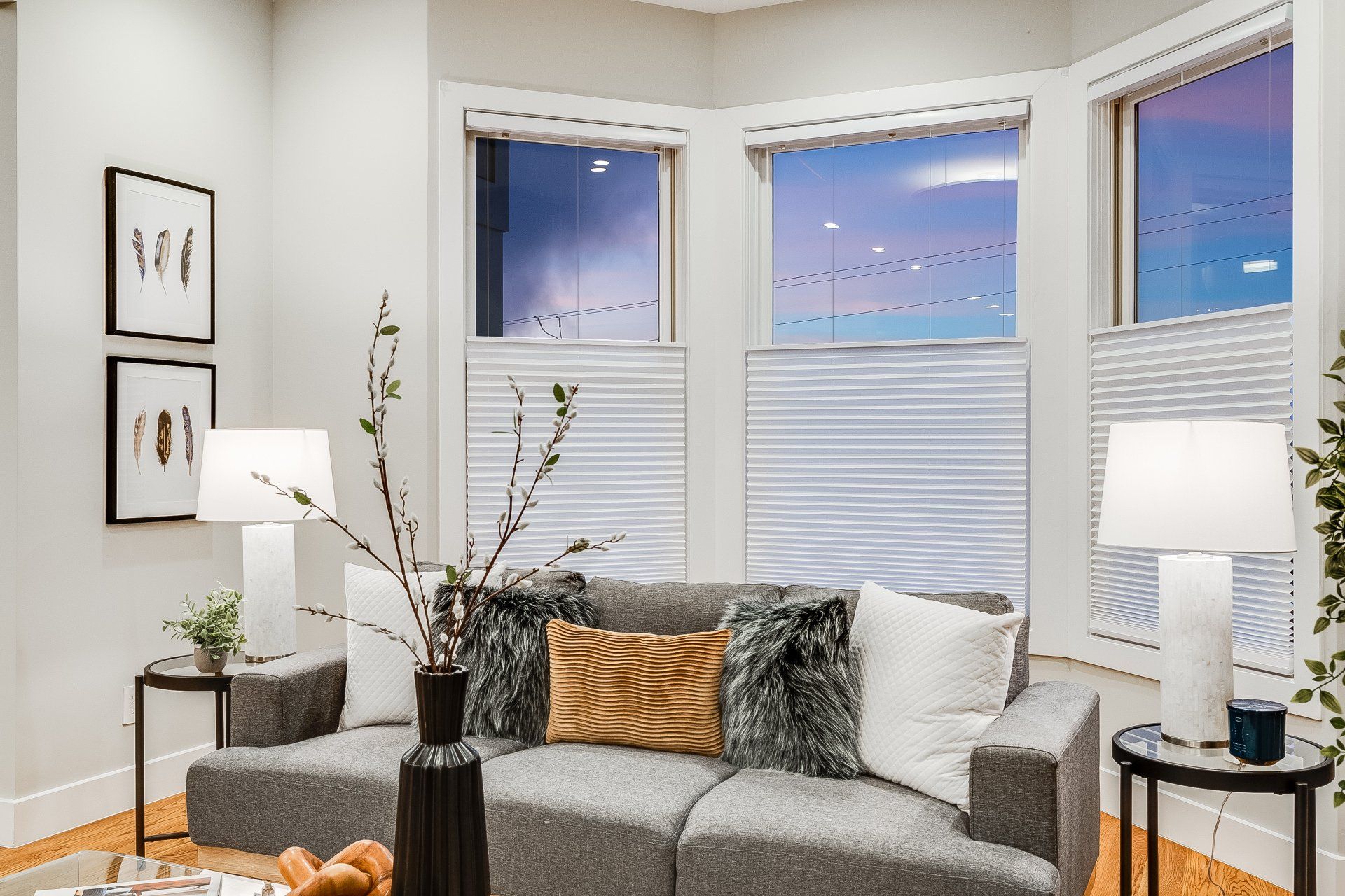 A living room with a couch , lamps , and windows.