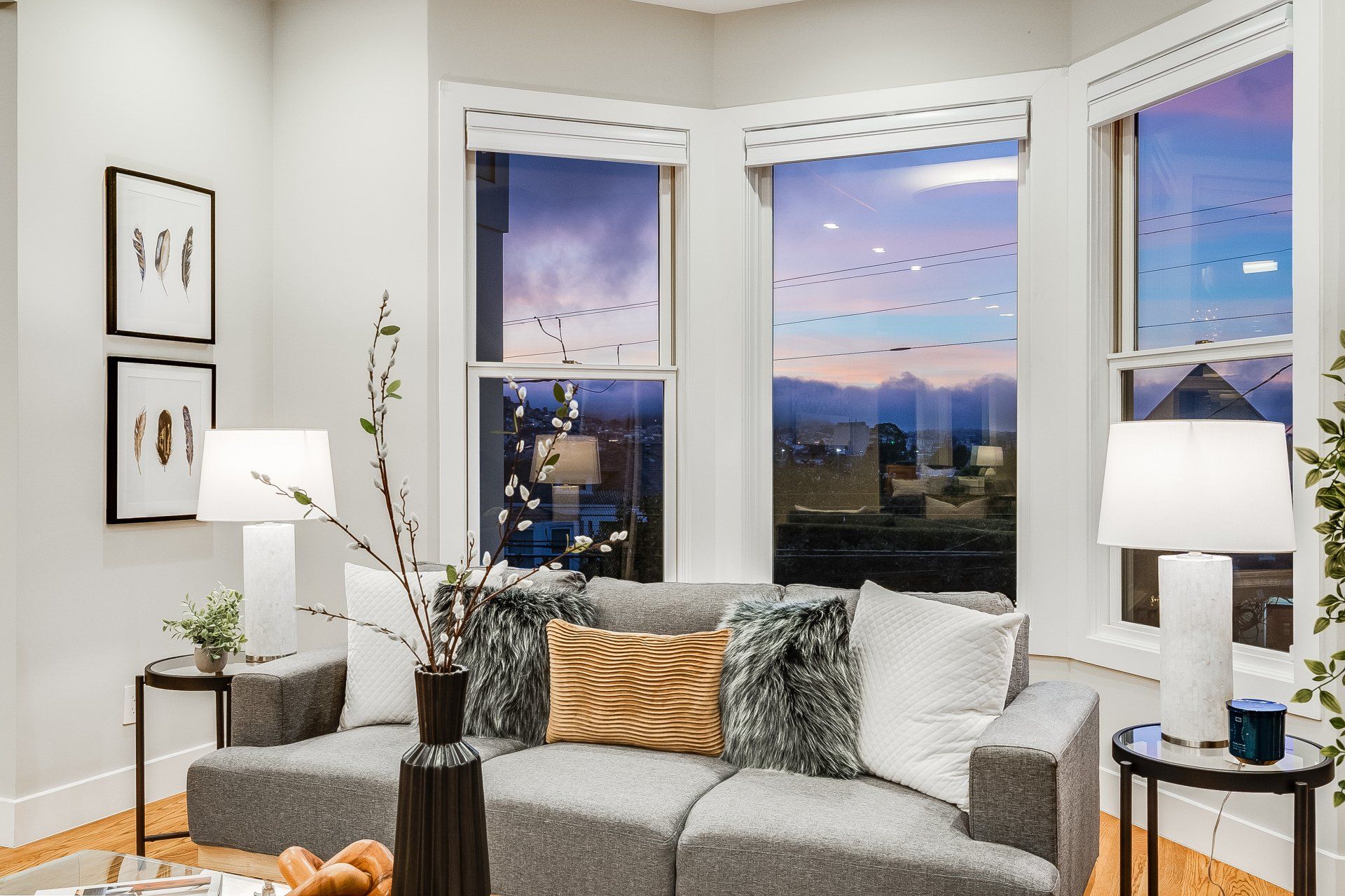 A living room with a couch , lamps , and a large window.