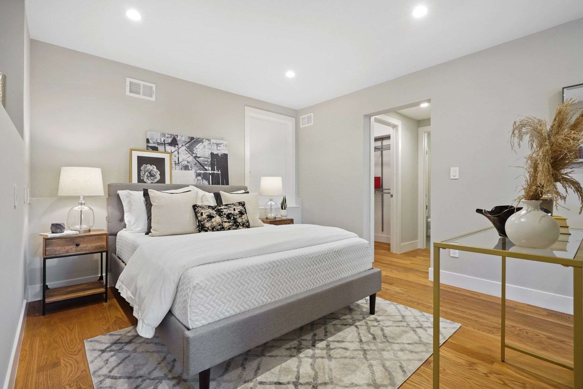 A bedroom with a bed , nightstand , table and rug.