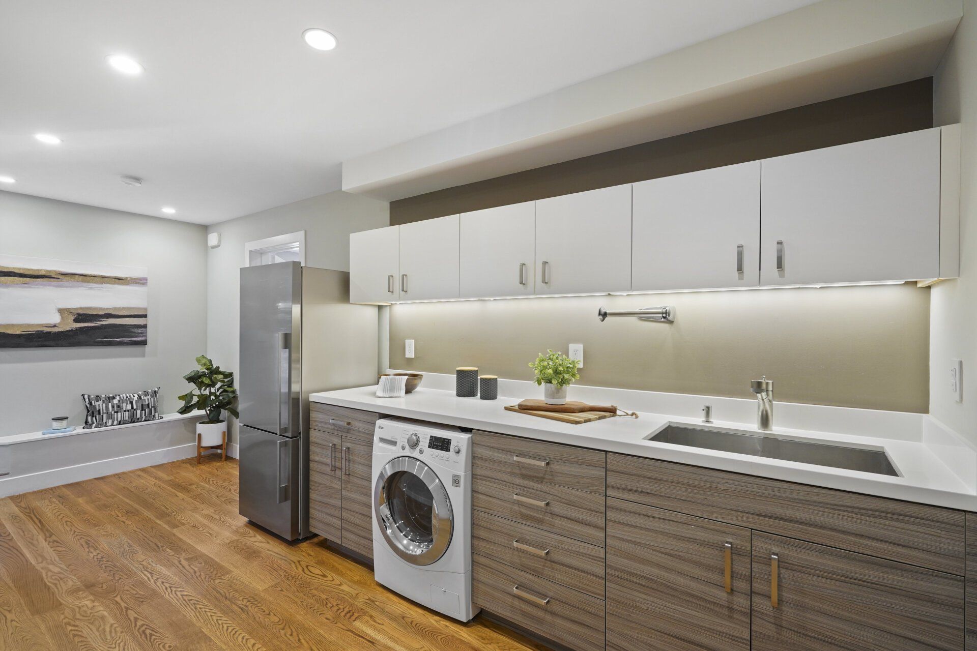A kitchen with a refrigerator, a washer and wooden cabinets.