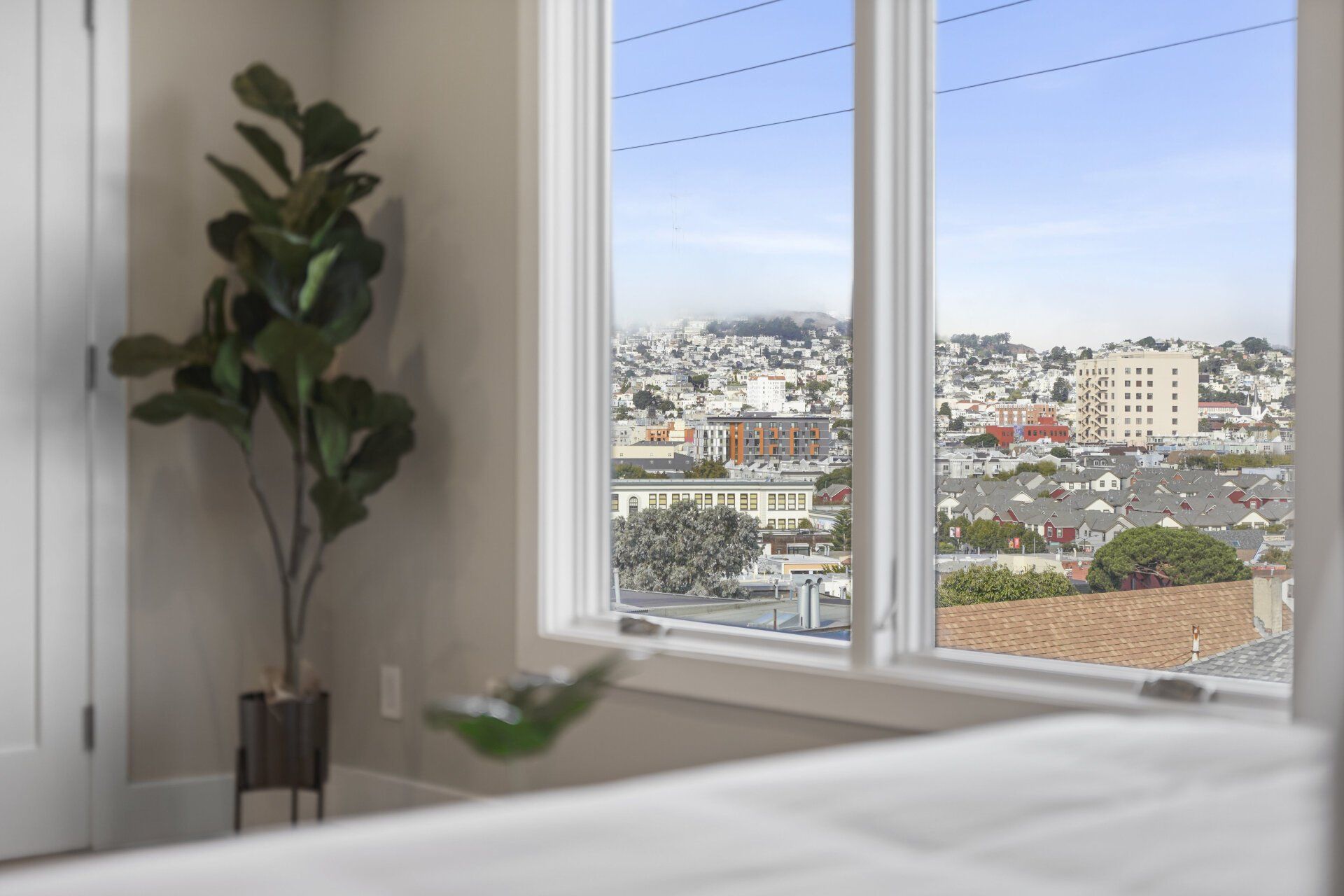 A bedroom with a large window and a view of the city.