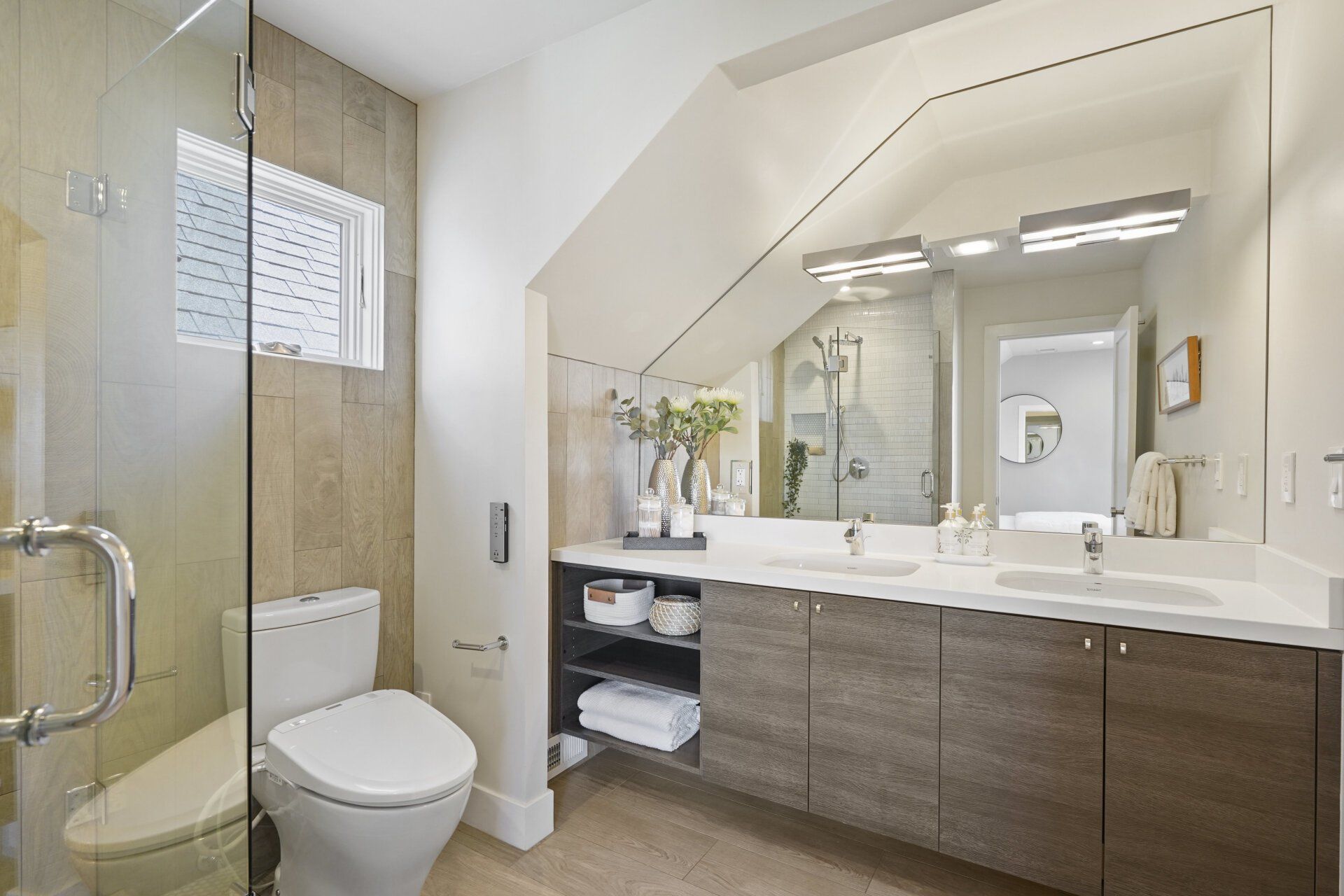 A bathroom with a toilet , sinks , and shower.