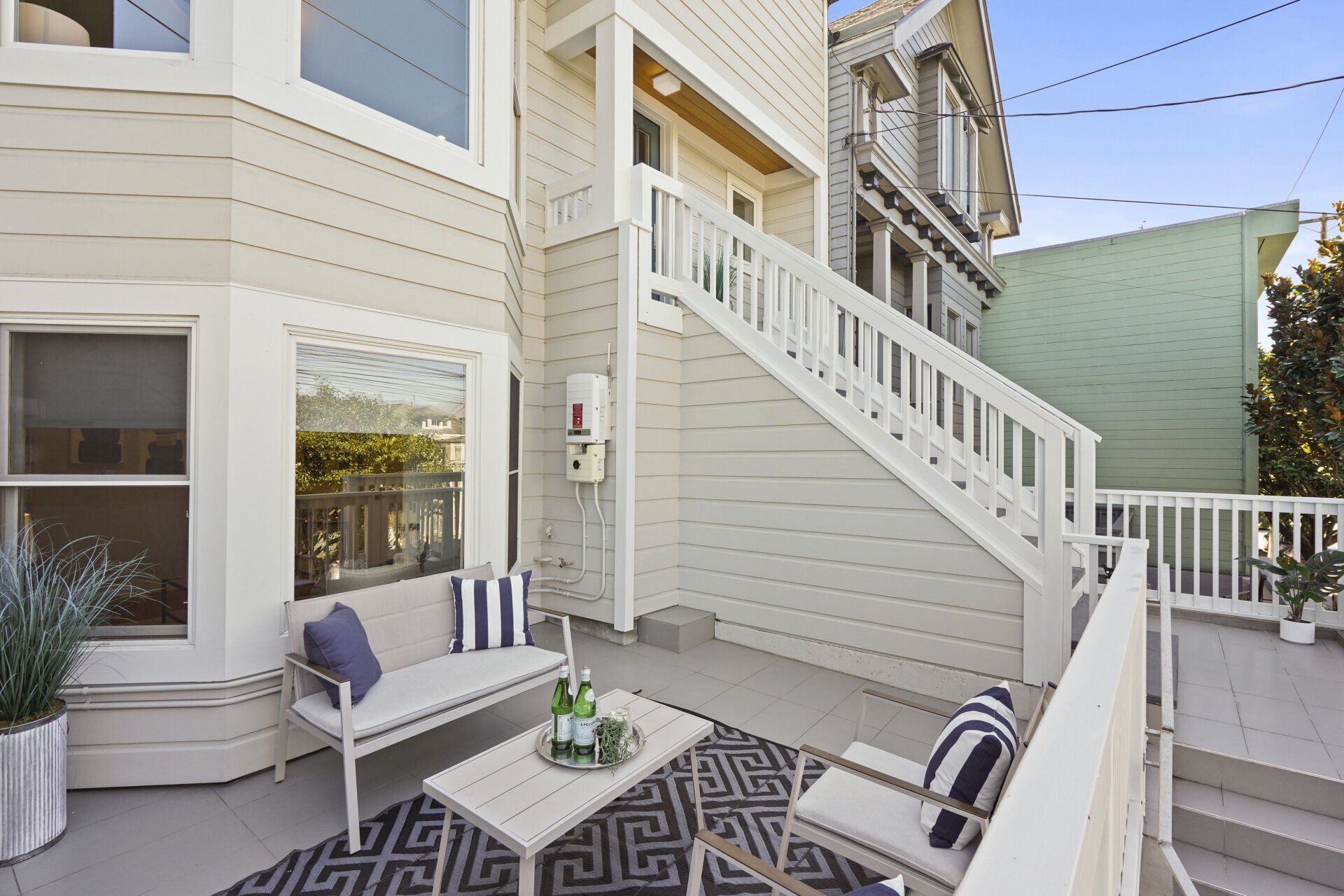 A white house with stairs and outdoor furniture.