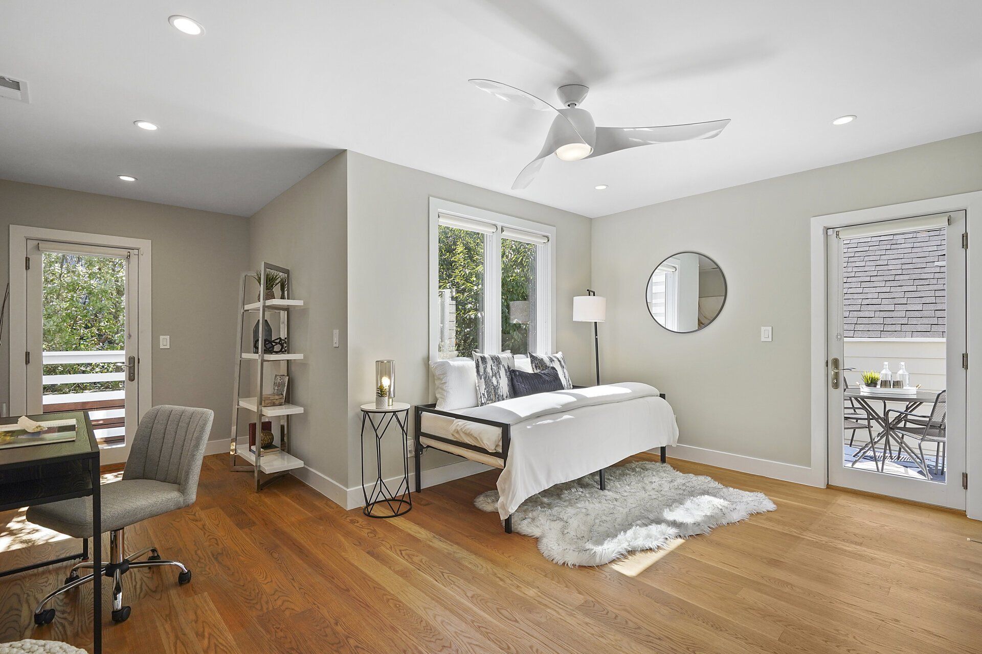 A room with a bed , desk , chair and ceiling fan.