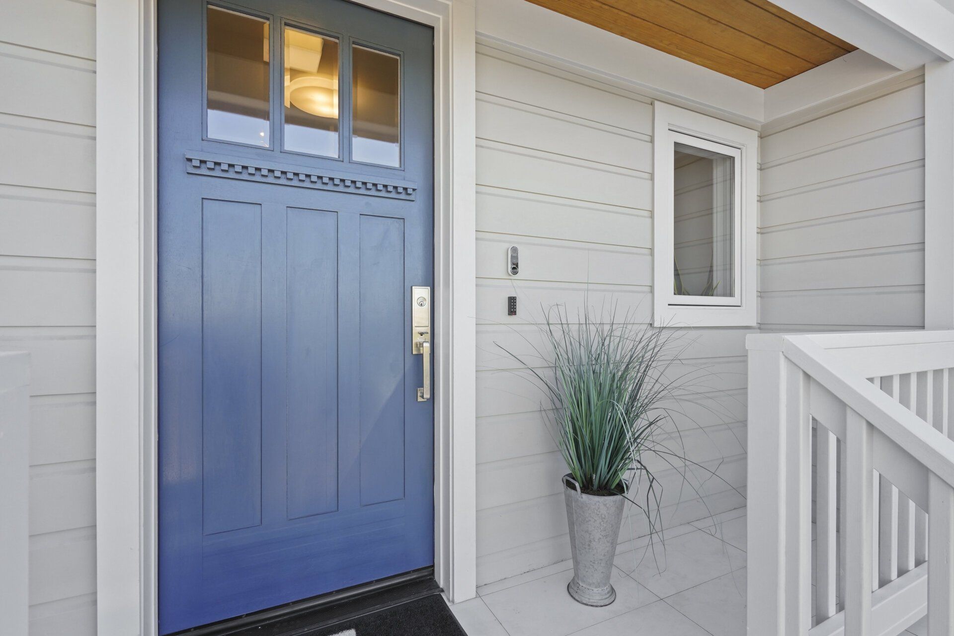 The front door of a house with a blue door and a potted plant in front of it.