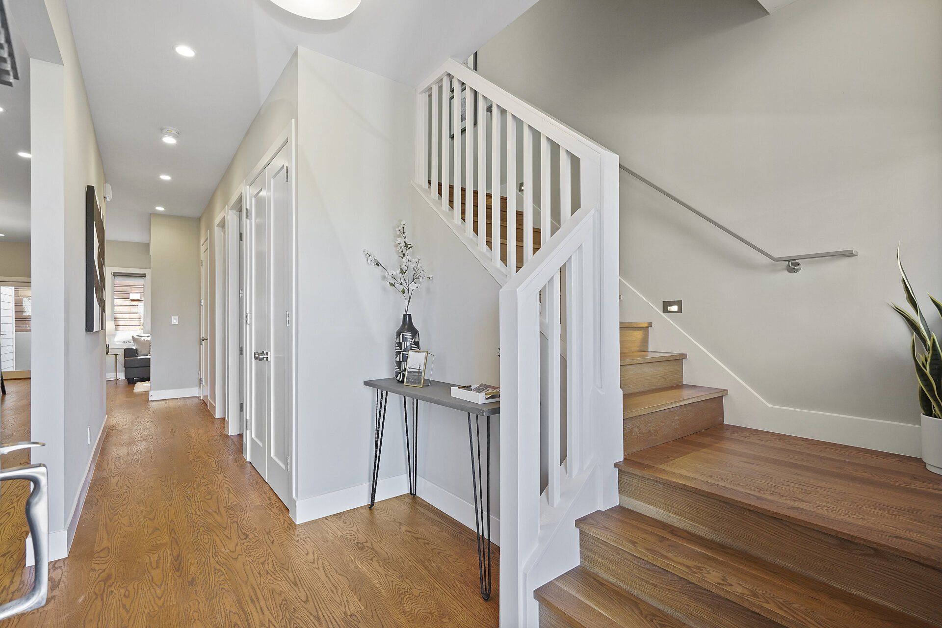 A hallway with wooden floors and a staircase.