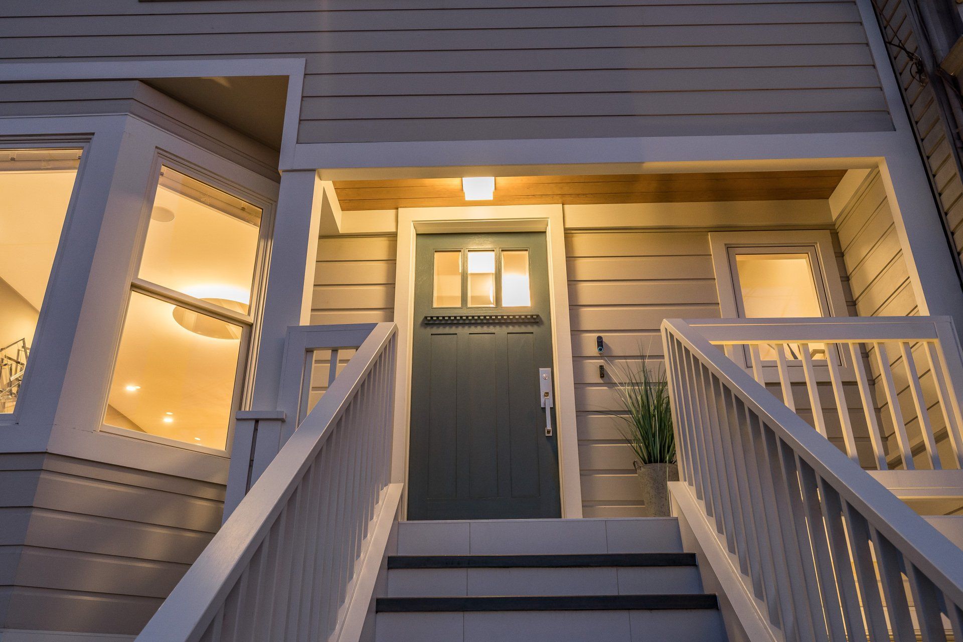 A two-story house exterior with a door, white trim, and steps leading up to a porch.