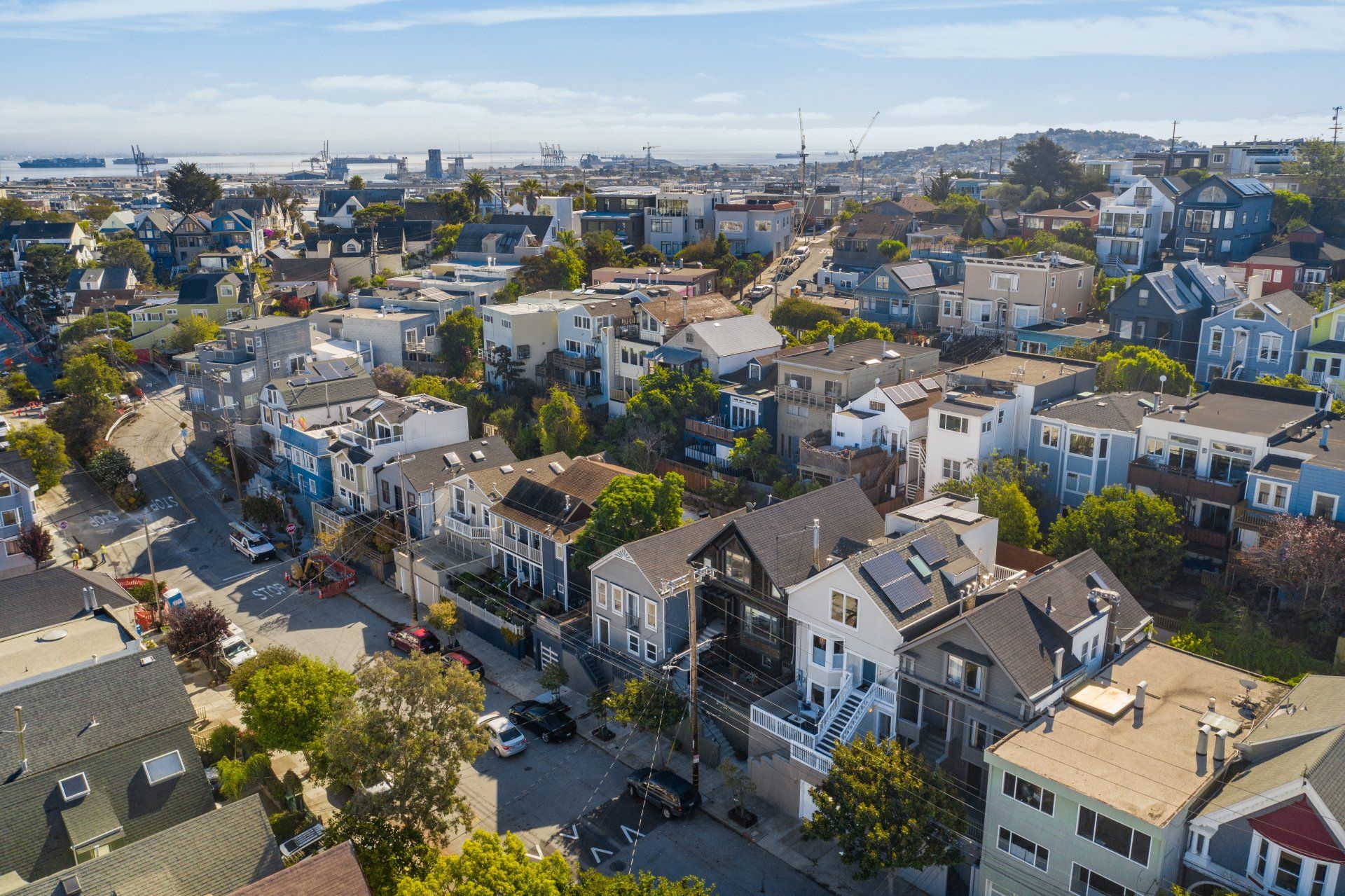 Aerial view of San Francisco houses on a sunny day, showing varied rooflines and street layout.