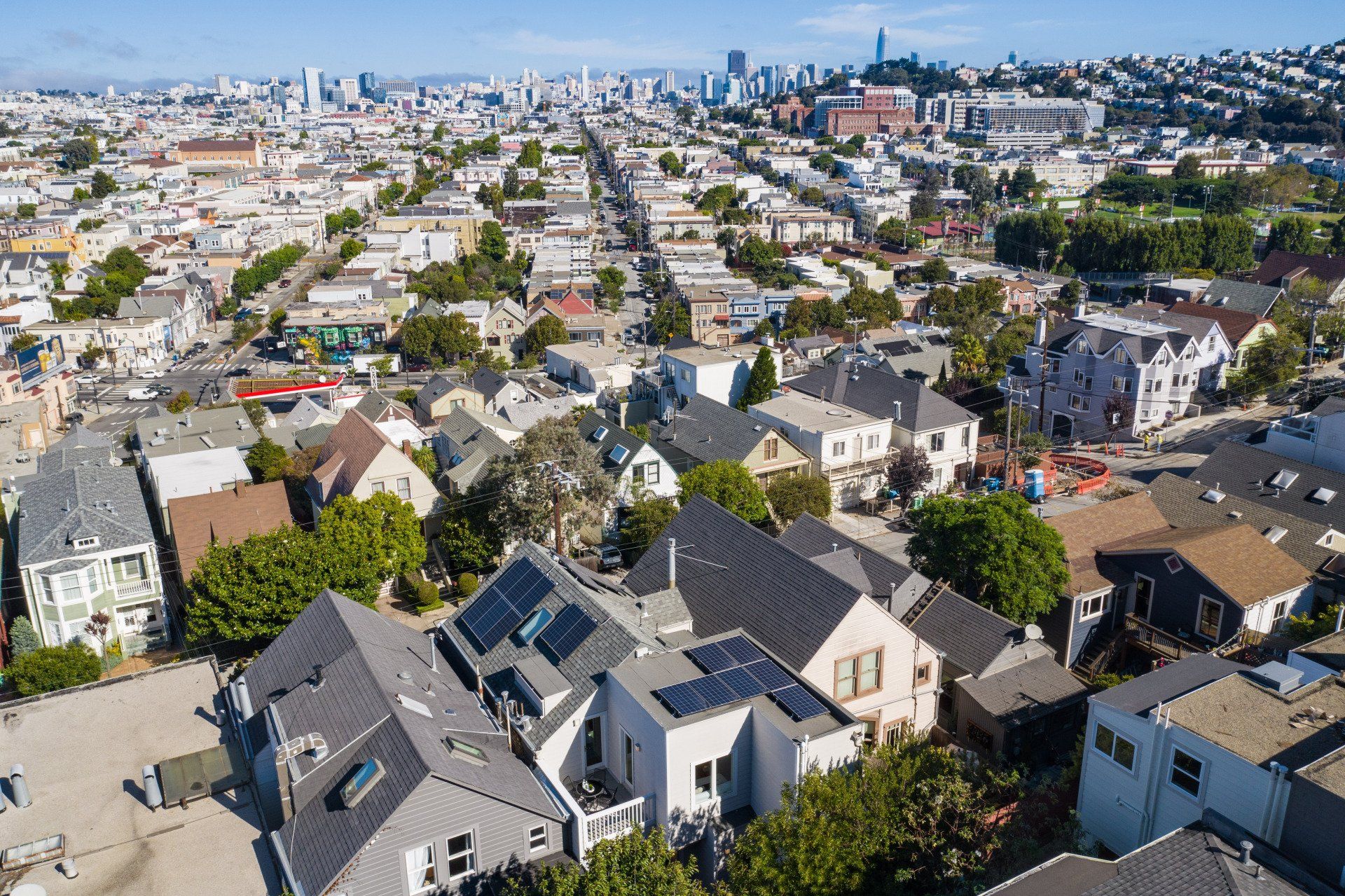 Aerial view of San Francisco residential neighborhood with houses and city skyline in the background.
