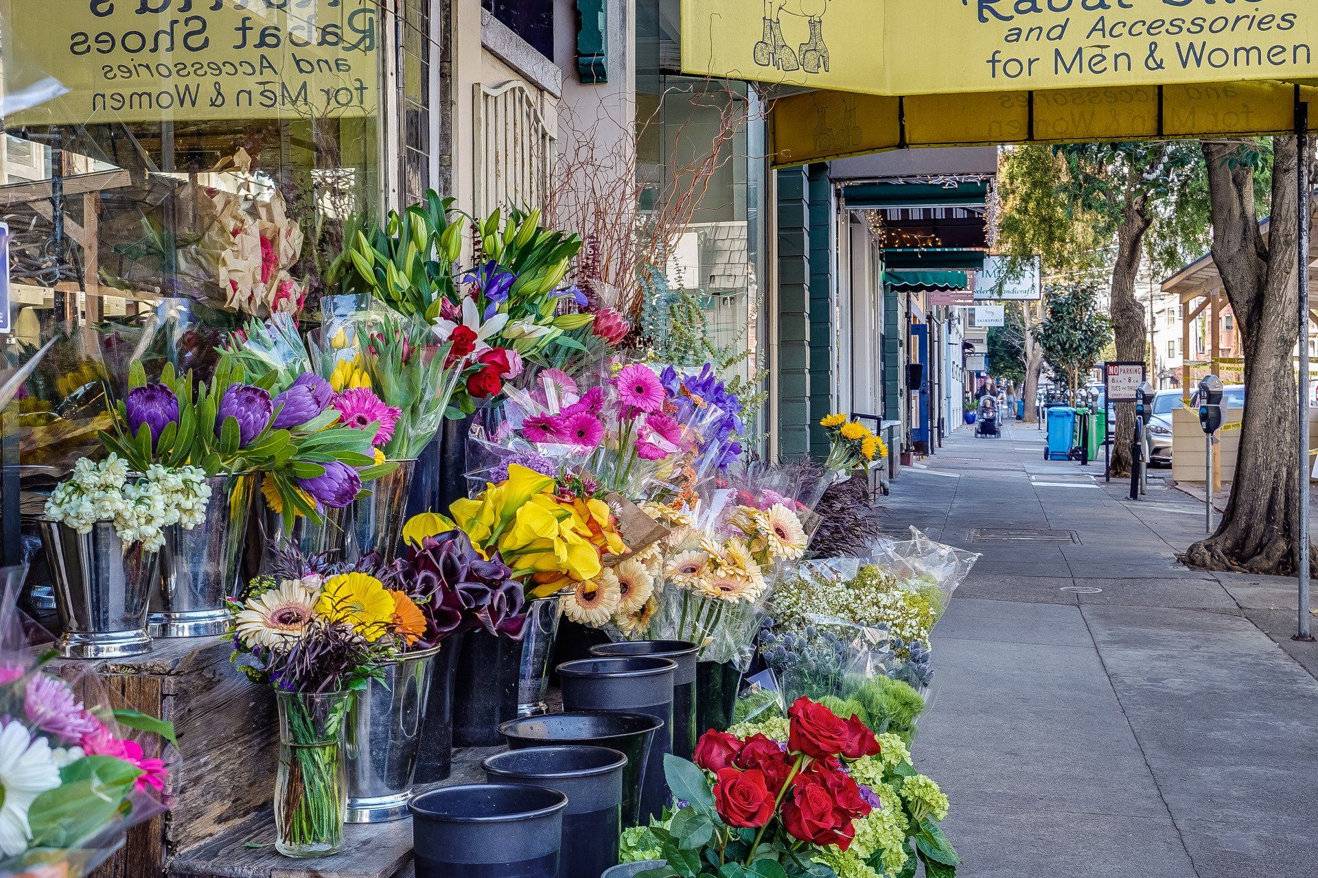 Flower shop display with colorful bouquets of flowers on a sidewalk in front of a building.