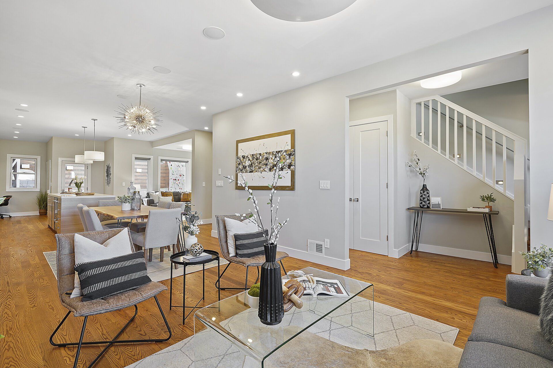 A living room with a couch , chairs , a coffee table and a staircase.