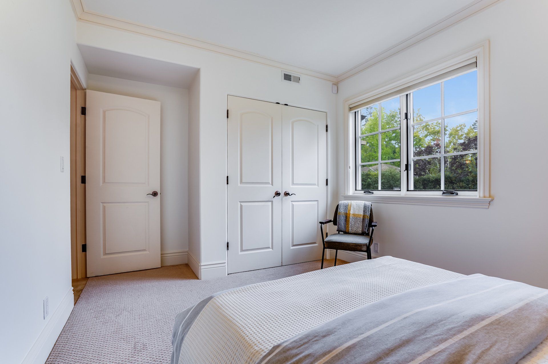 A bedroom with a bed a chair and a window