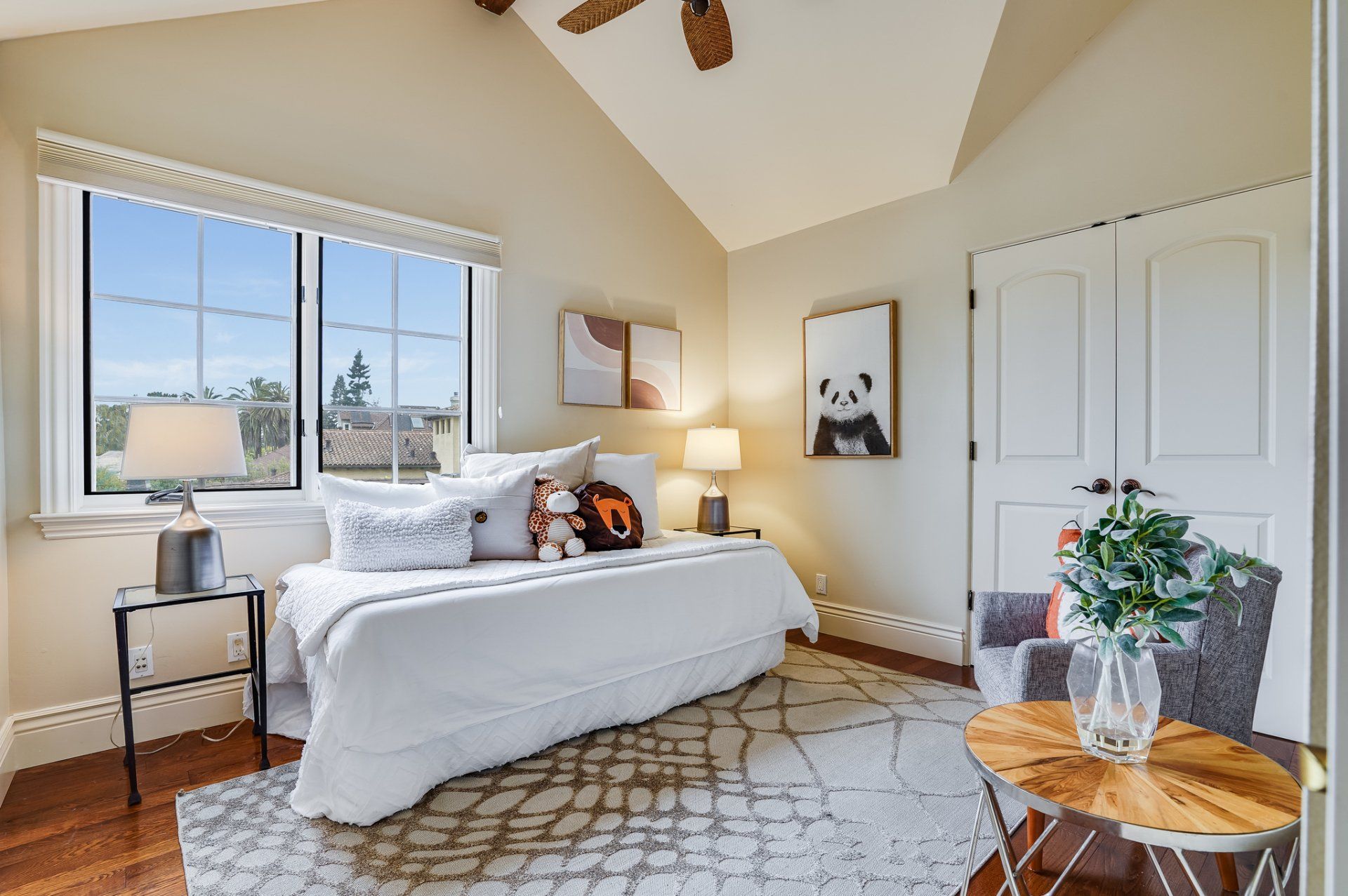 A bedroom with a bed , chair , table and ceiling fan.