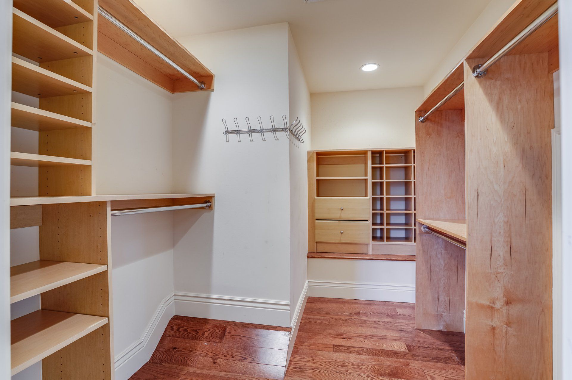 A walk in closet with wooden shelves and hardwood floors