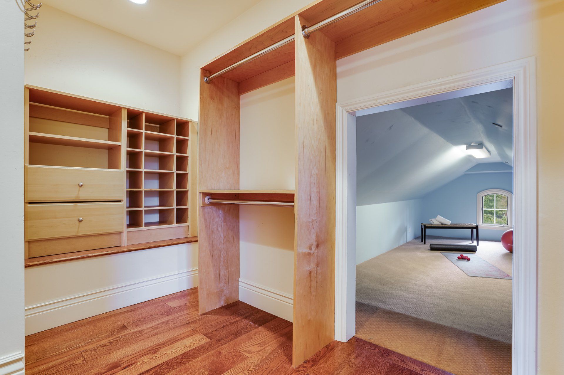A walk in closet with a bedroom in the background