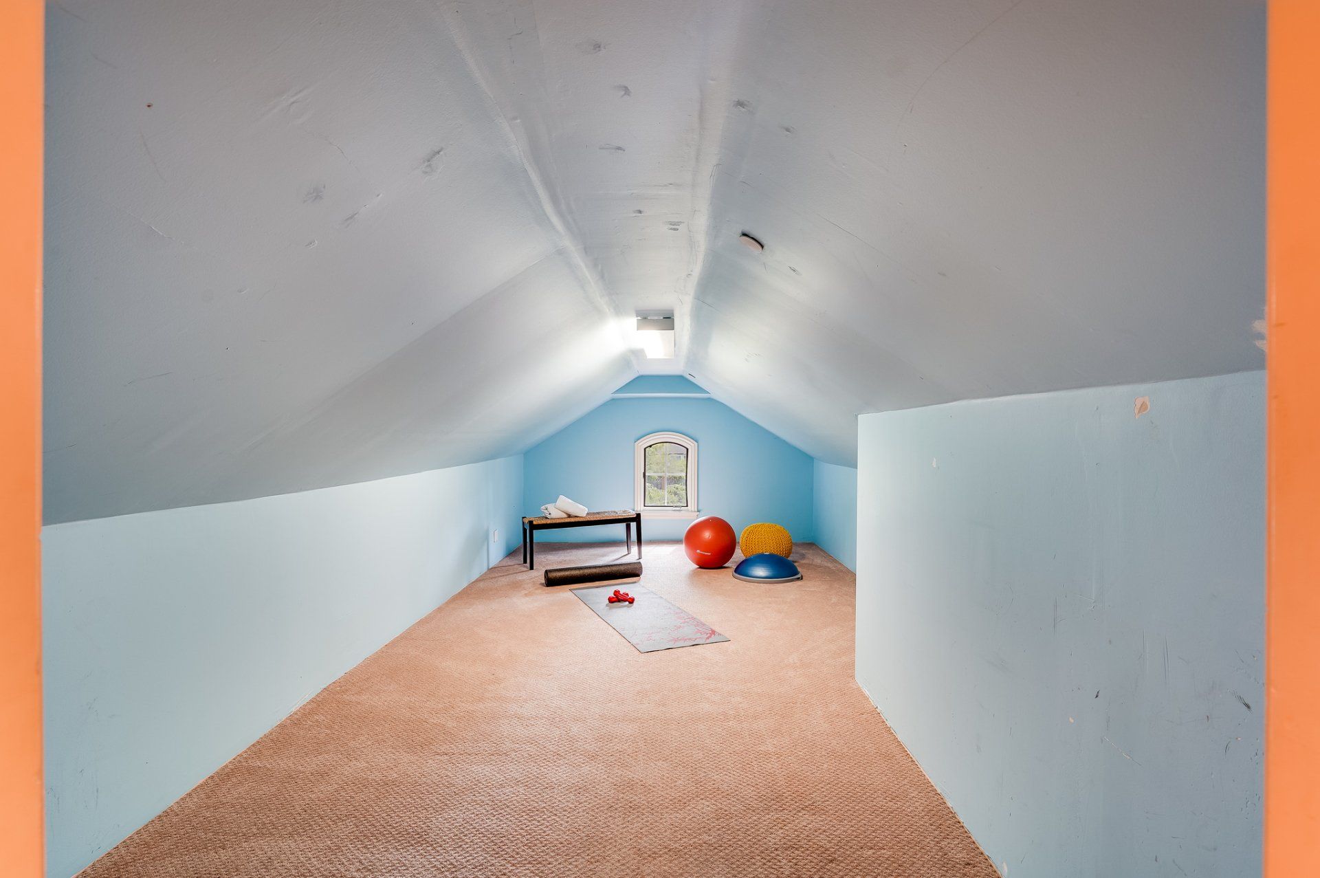 An attic with a yoga mat and balls on the floor