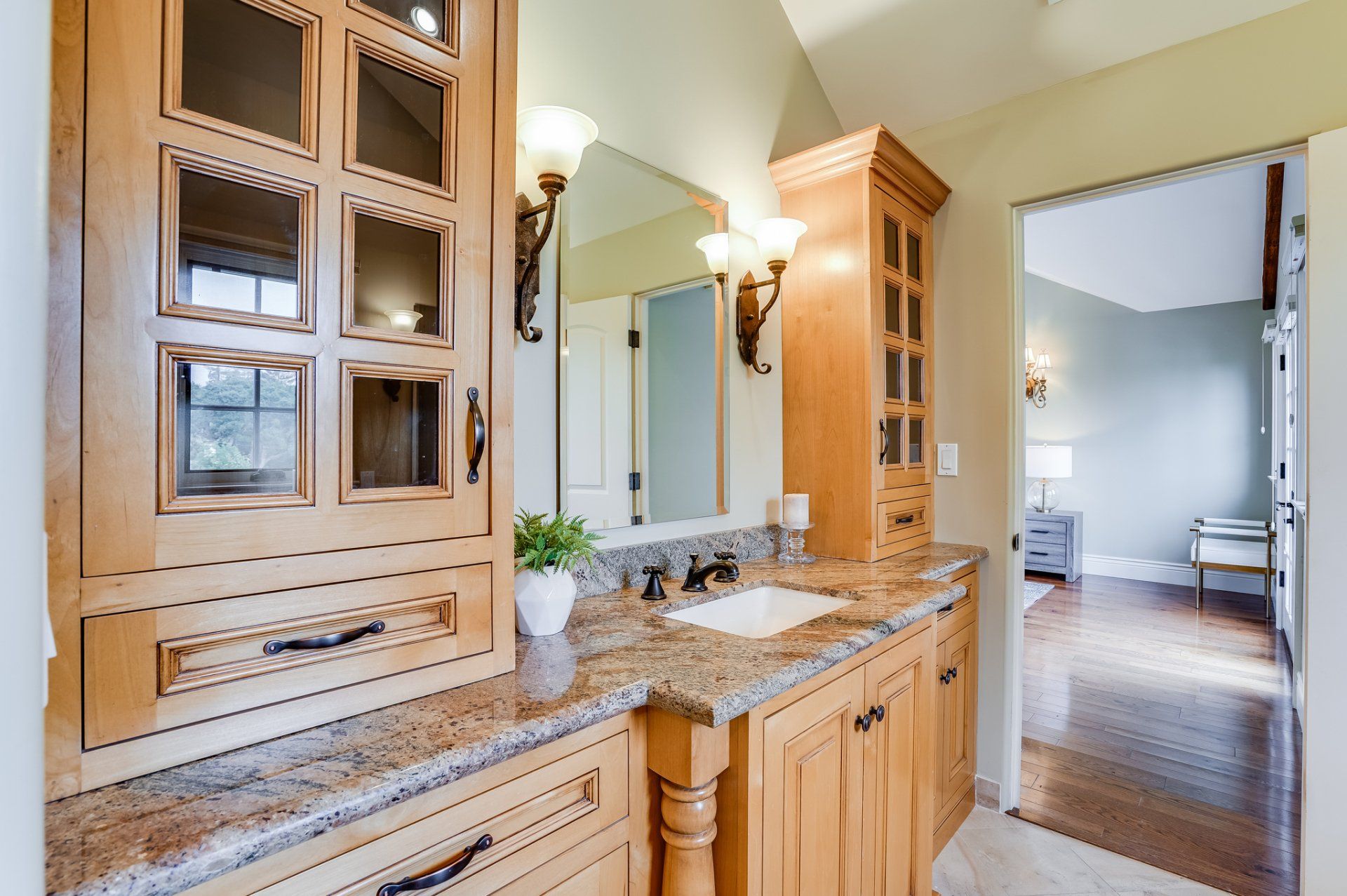 A bathroom with a sink , mirror and cabinets