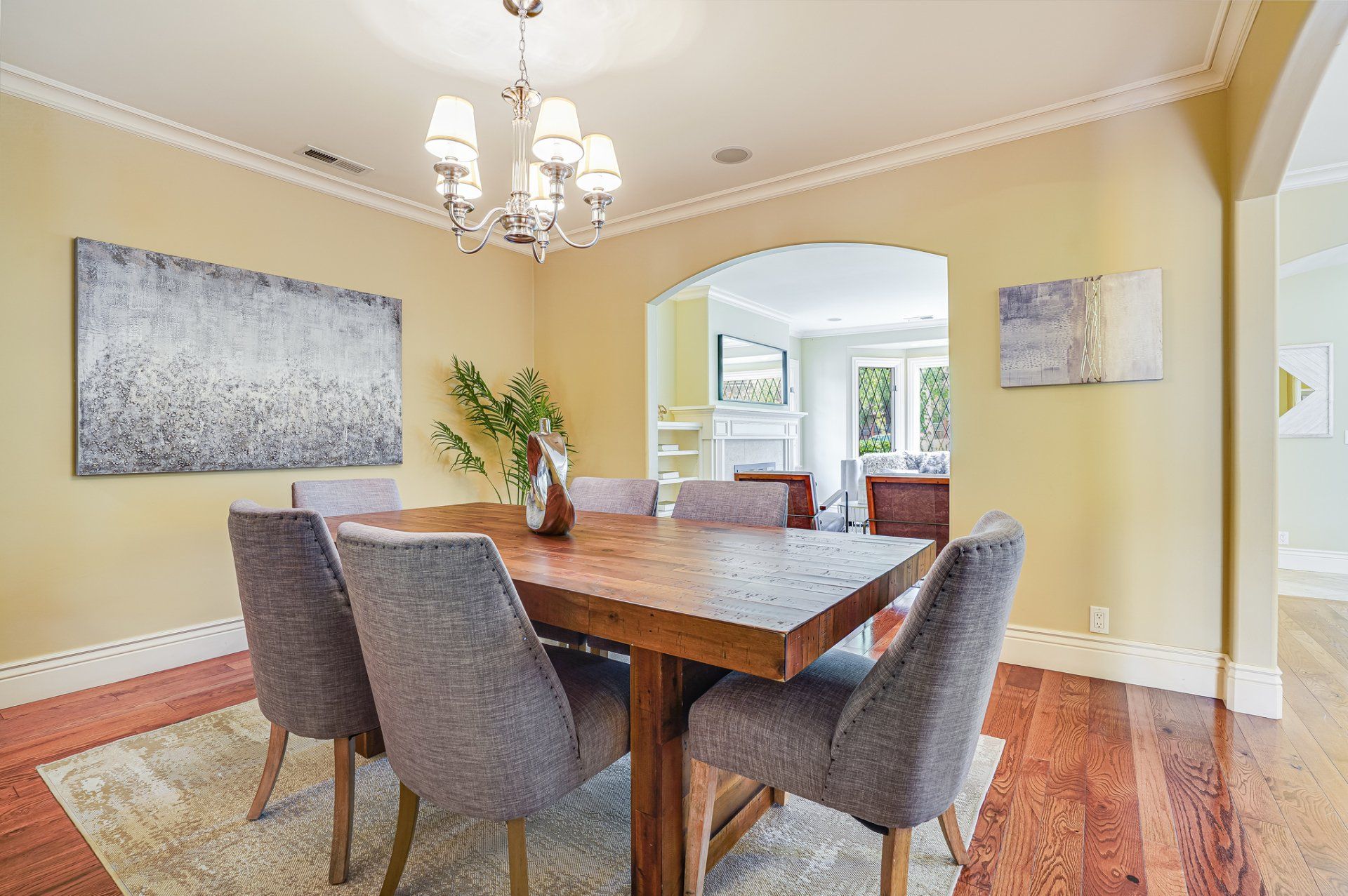 A dining room with a wooden table and chairs and a chandelier.