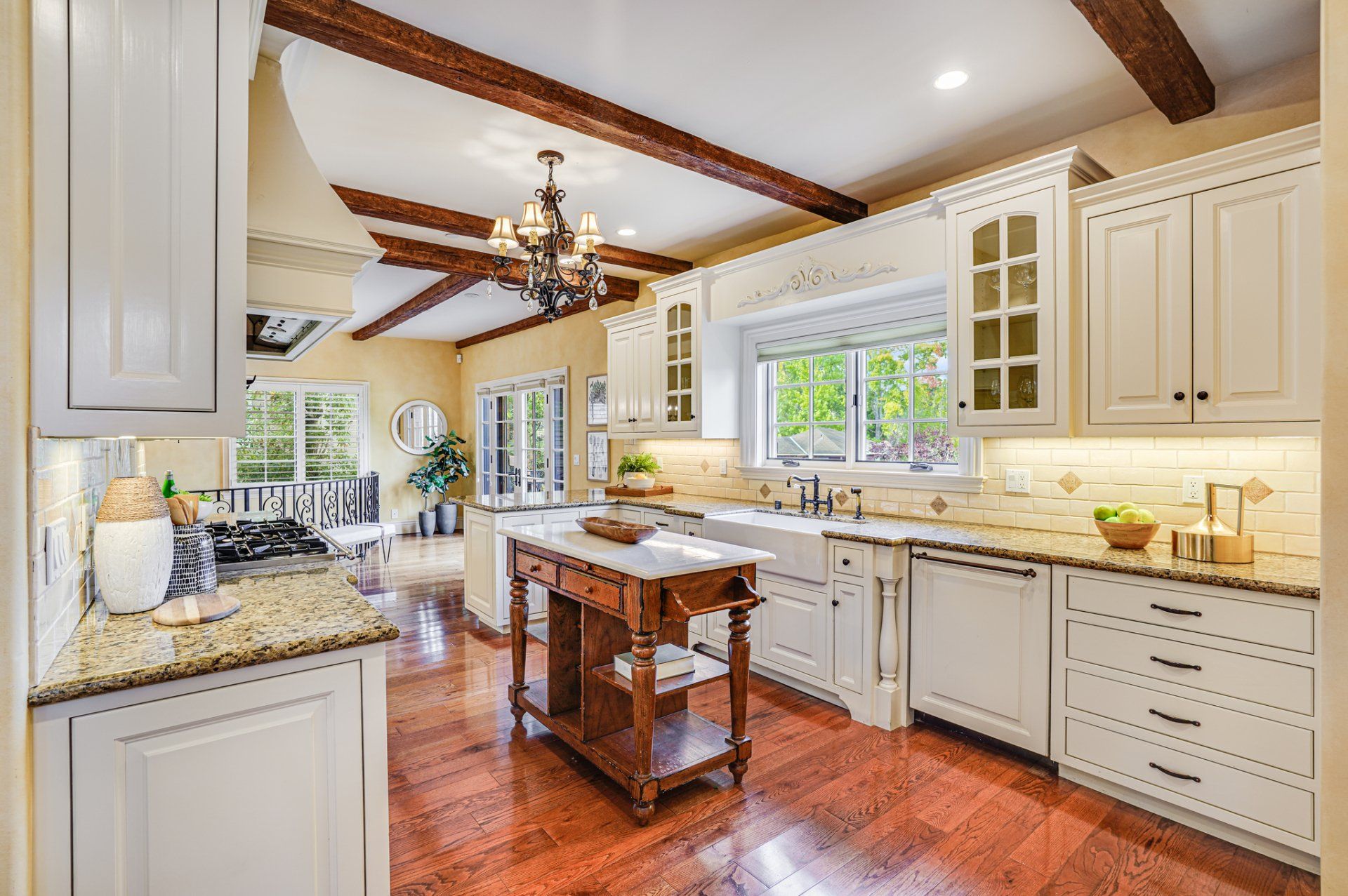 A kitchen with white cabinets and hardwood floors and a wooden island.