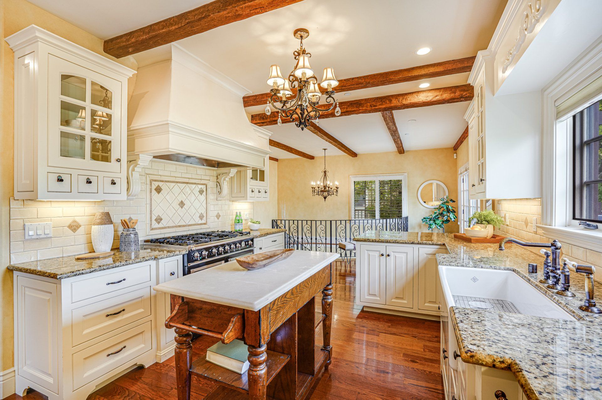 A kitchen with white cabinets , granite counter tops , and a wooden island.