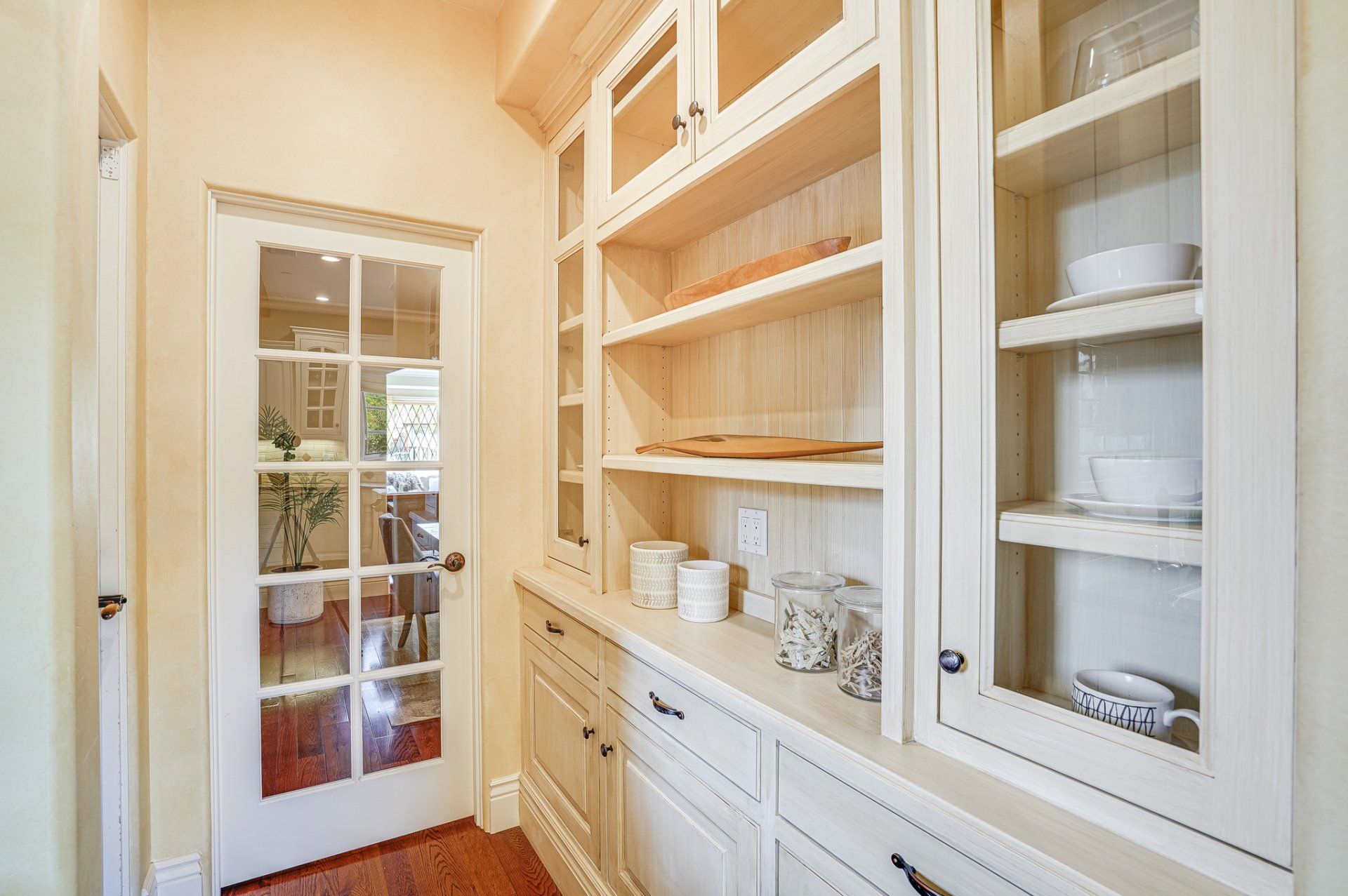 A kitchen with white cabinets and glass doors