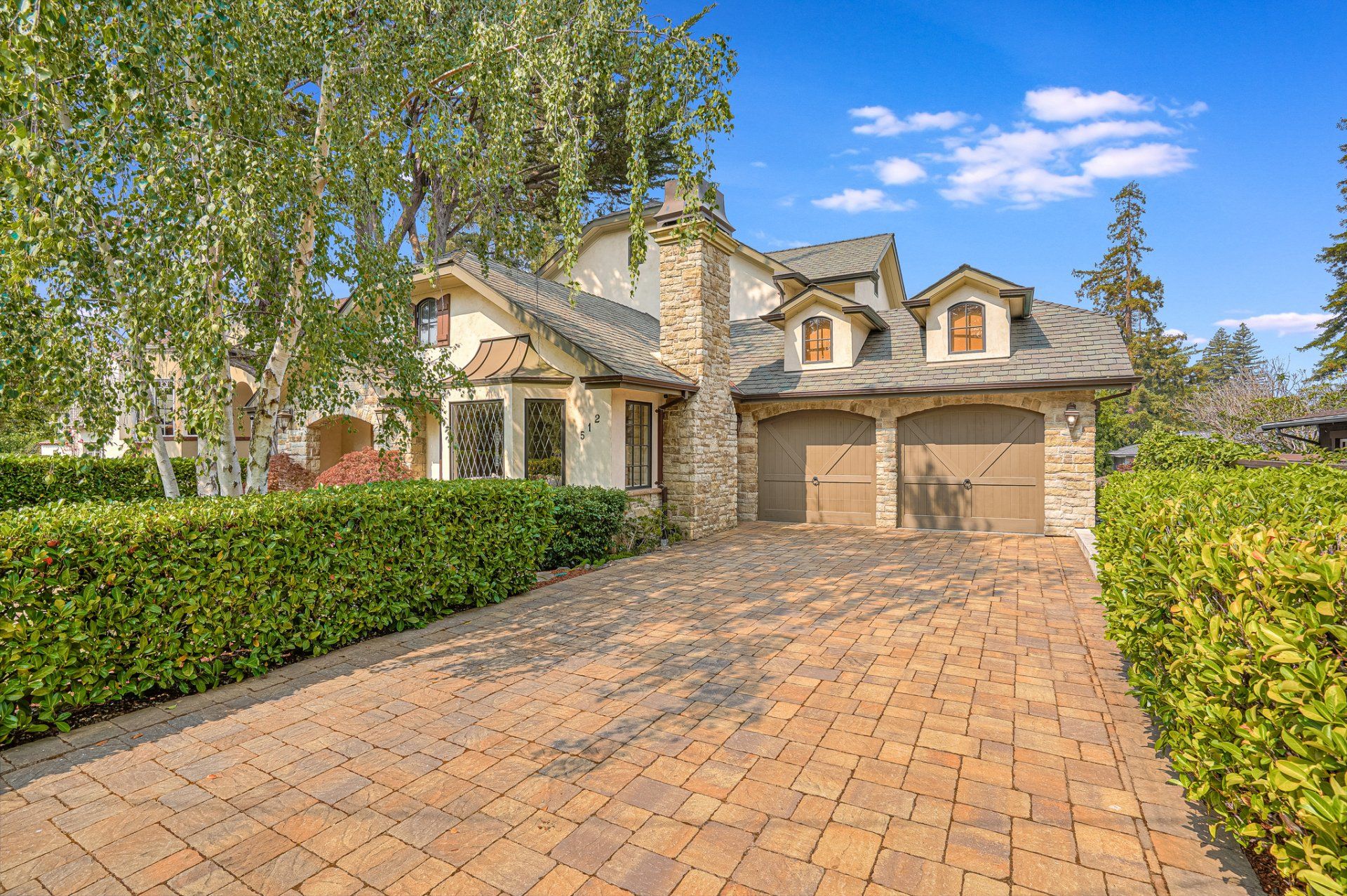 A large house with a brick driveway leading to it.