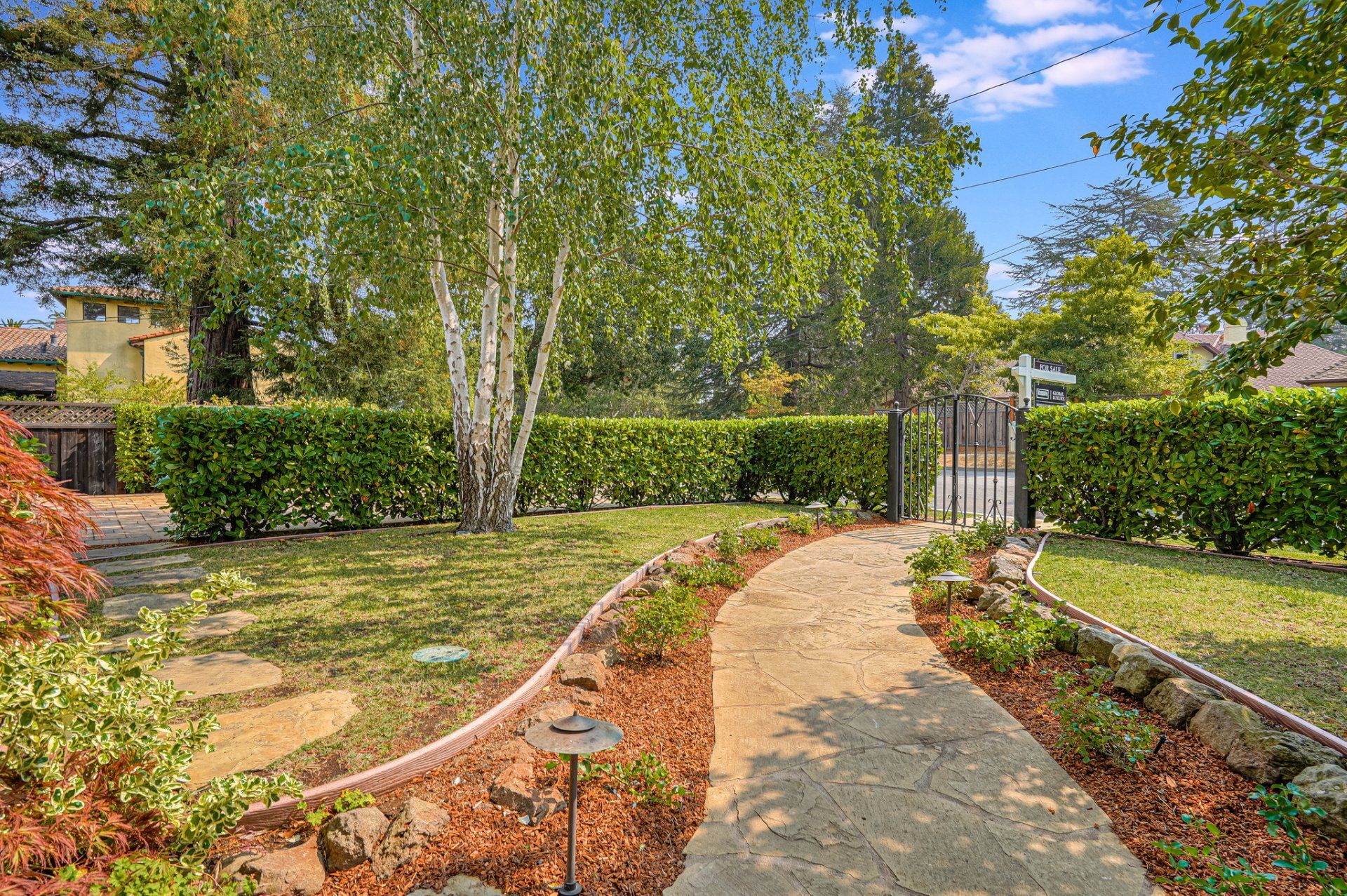 There is a path leading to a gate in the backyard.