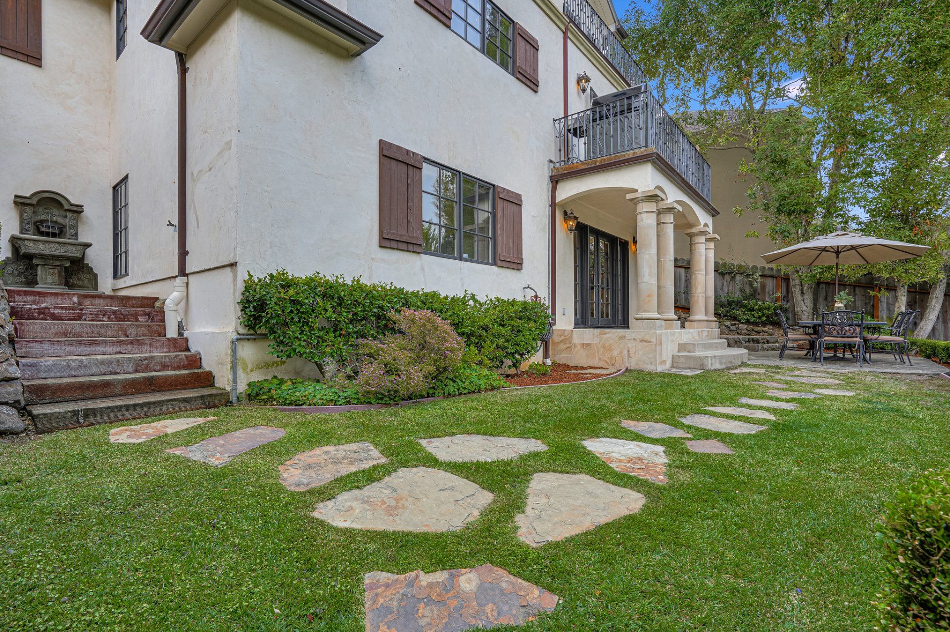 A large white house with a lush green lawn and a stone walkway leading to it.