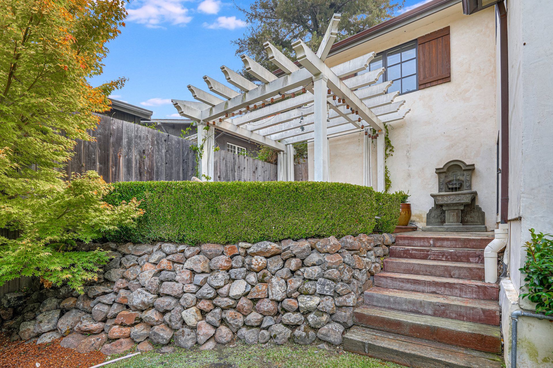 There is a stone wall in the backyard with stairs leading up to it.
