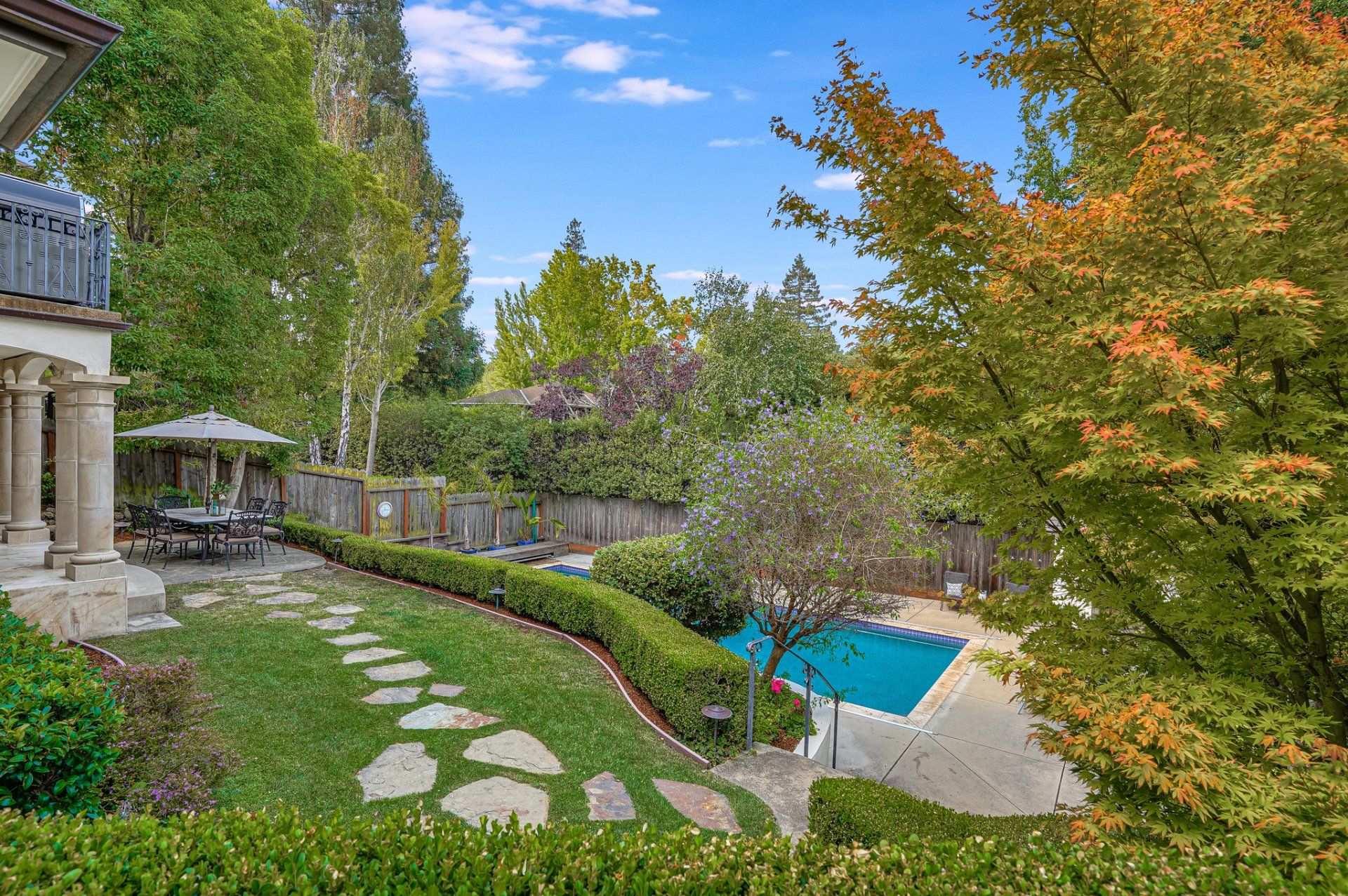 There is a large swimming pool in the backyard of a house.