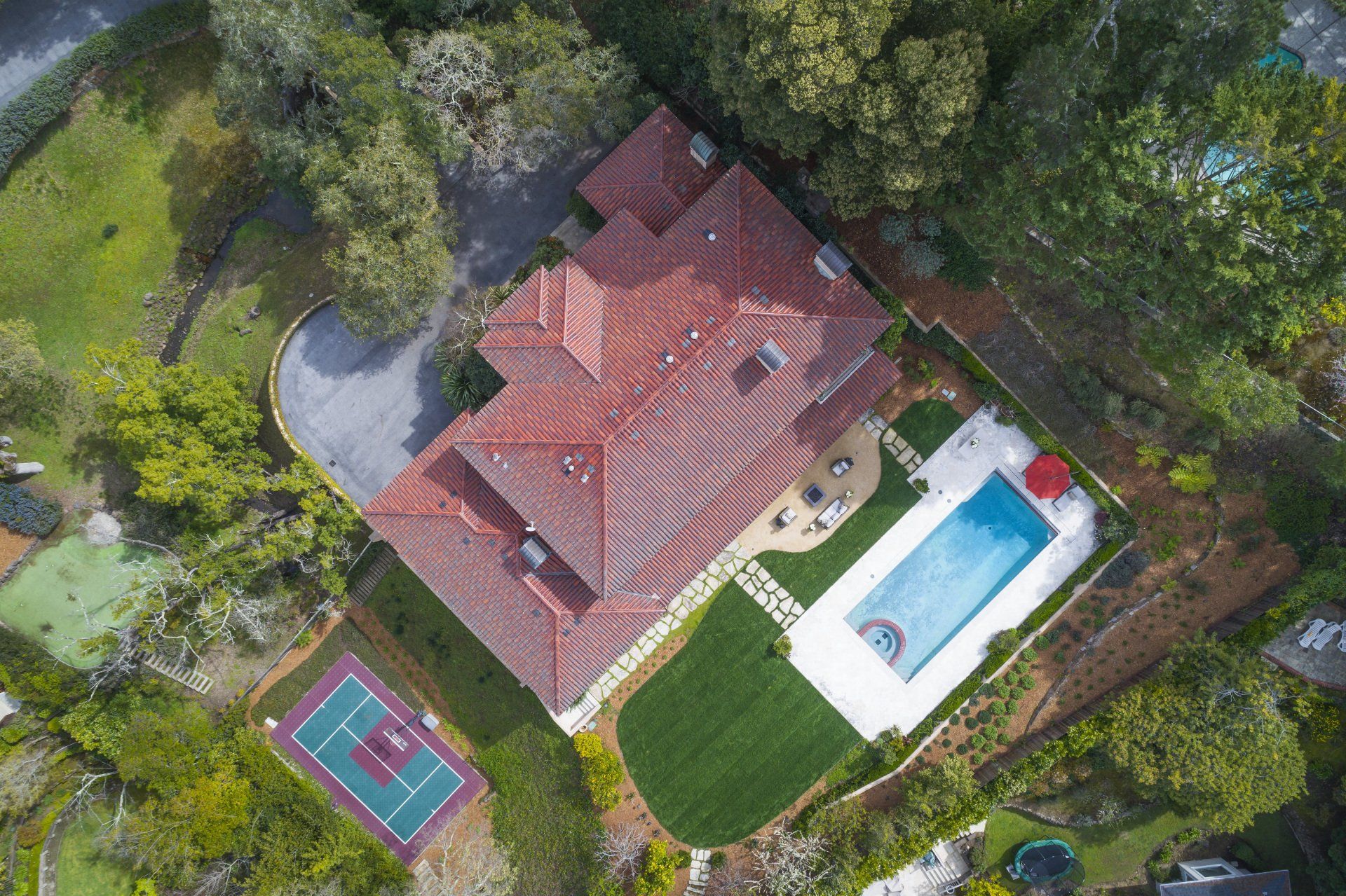 An aerial view of a large house with a pool and tennis court.