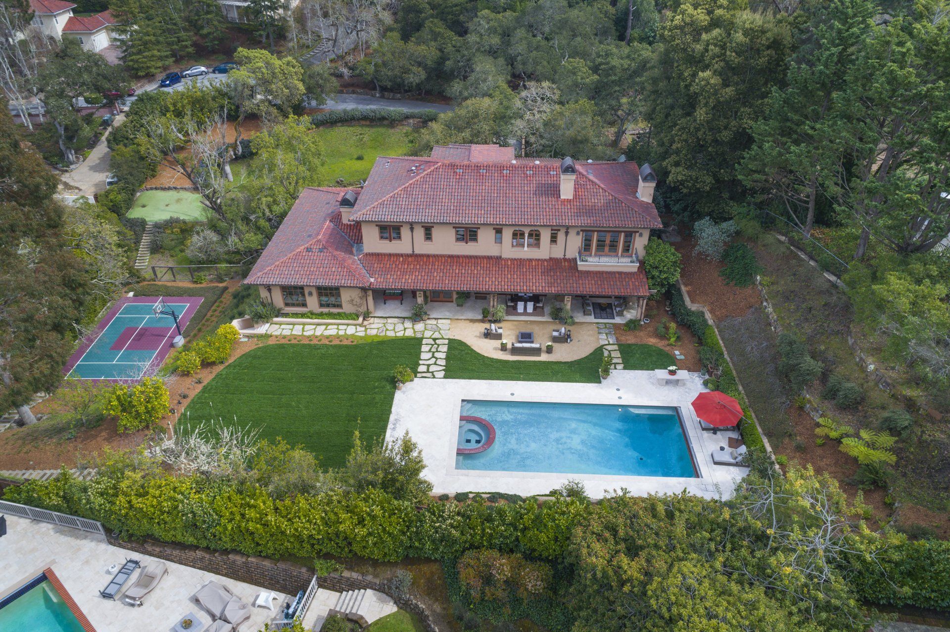 An aerial view of a large house with a swimming pool and tennis court.