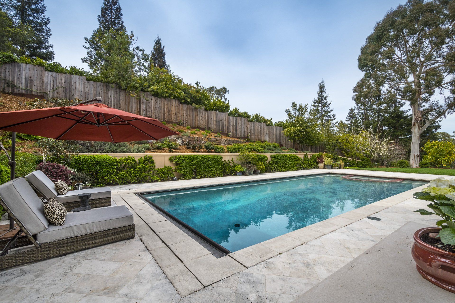 A large swimming pool with a red umbrella in the backyard