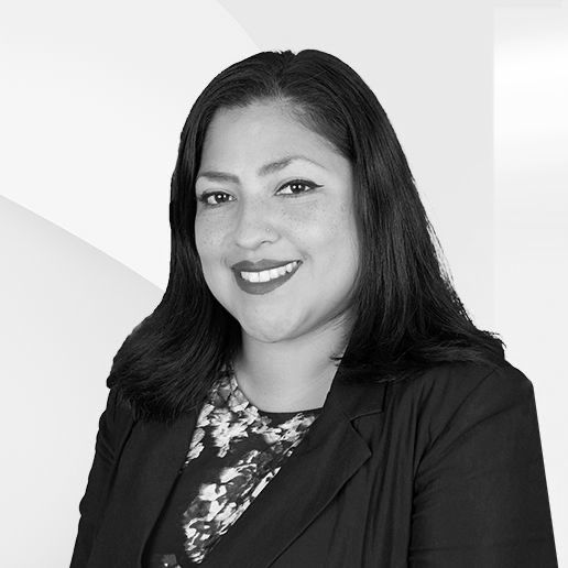 A woman in a suit is smiling in a black and white photo.