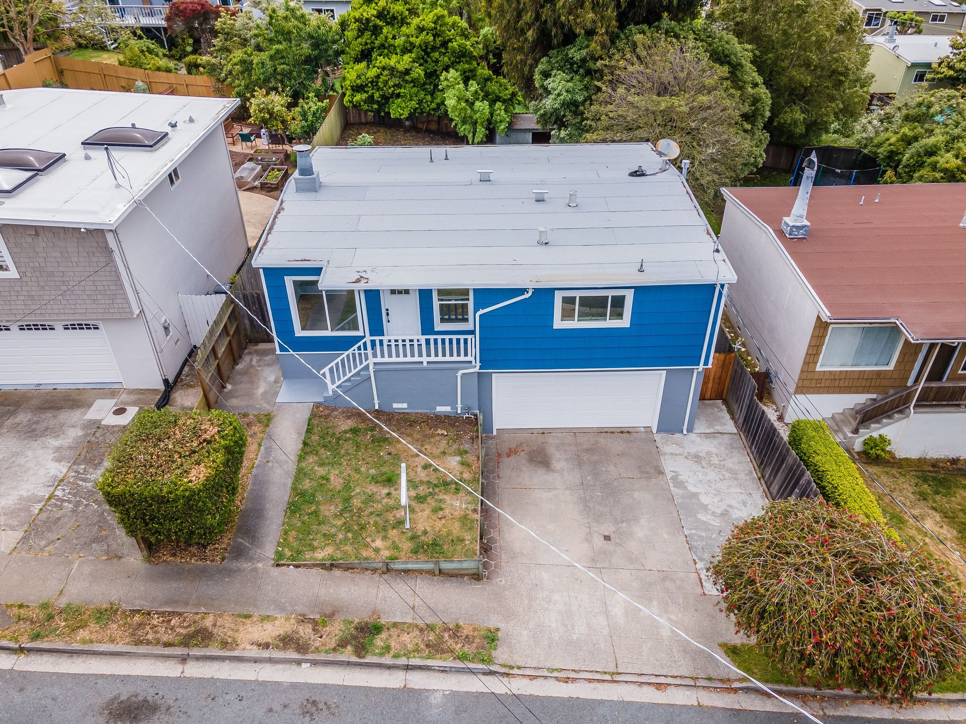 An aerial view of a blue house with a white garage.