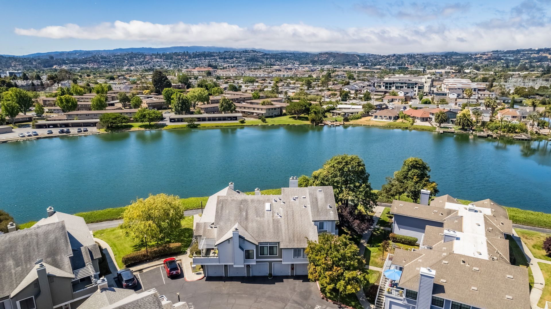 An aerial view of a lake with houses in the foreground and a city in the background.