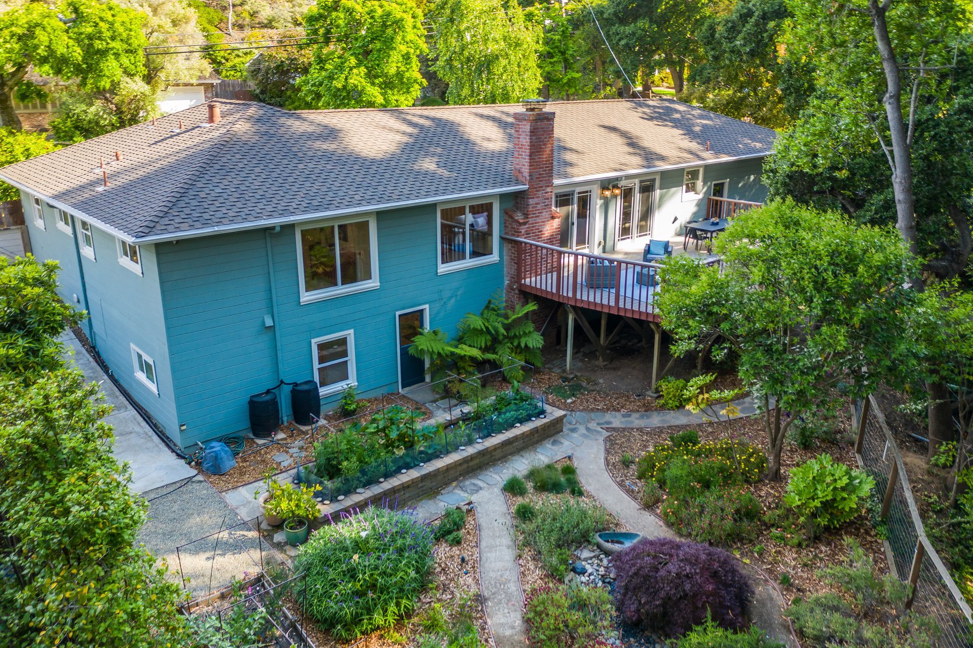 An aerial view of a large blue house surrounded by trees.
