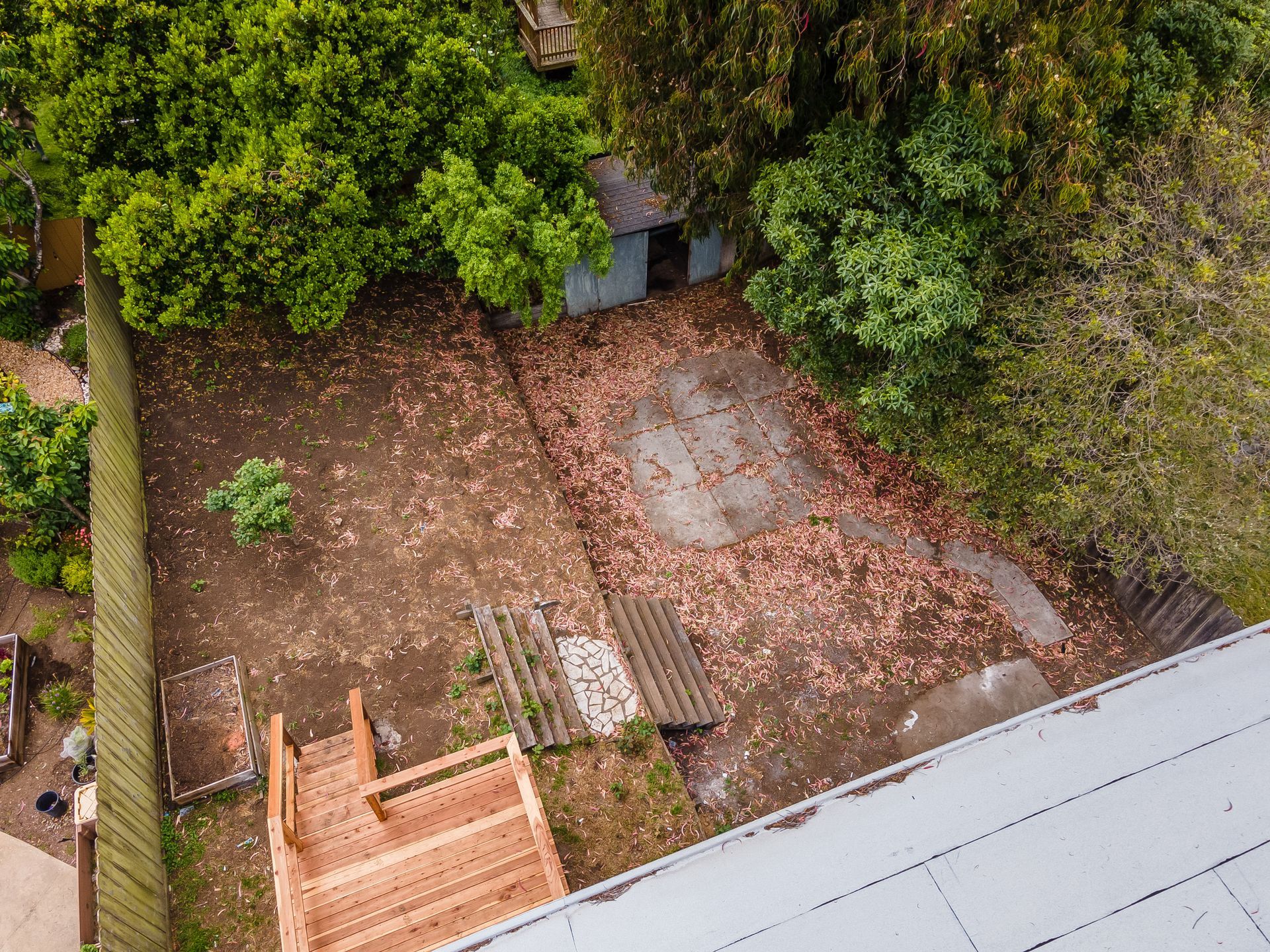 An aerial view of a backyard with a wooden deck and stairs.