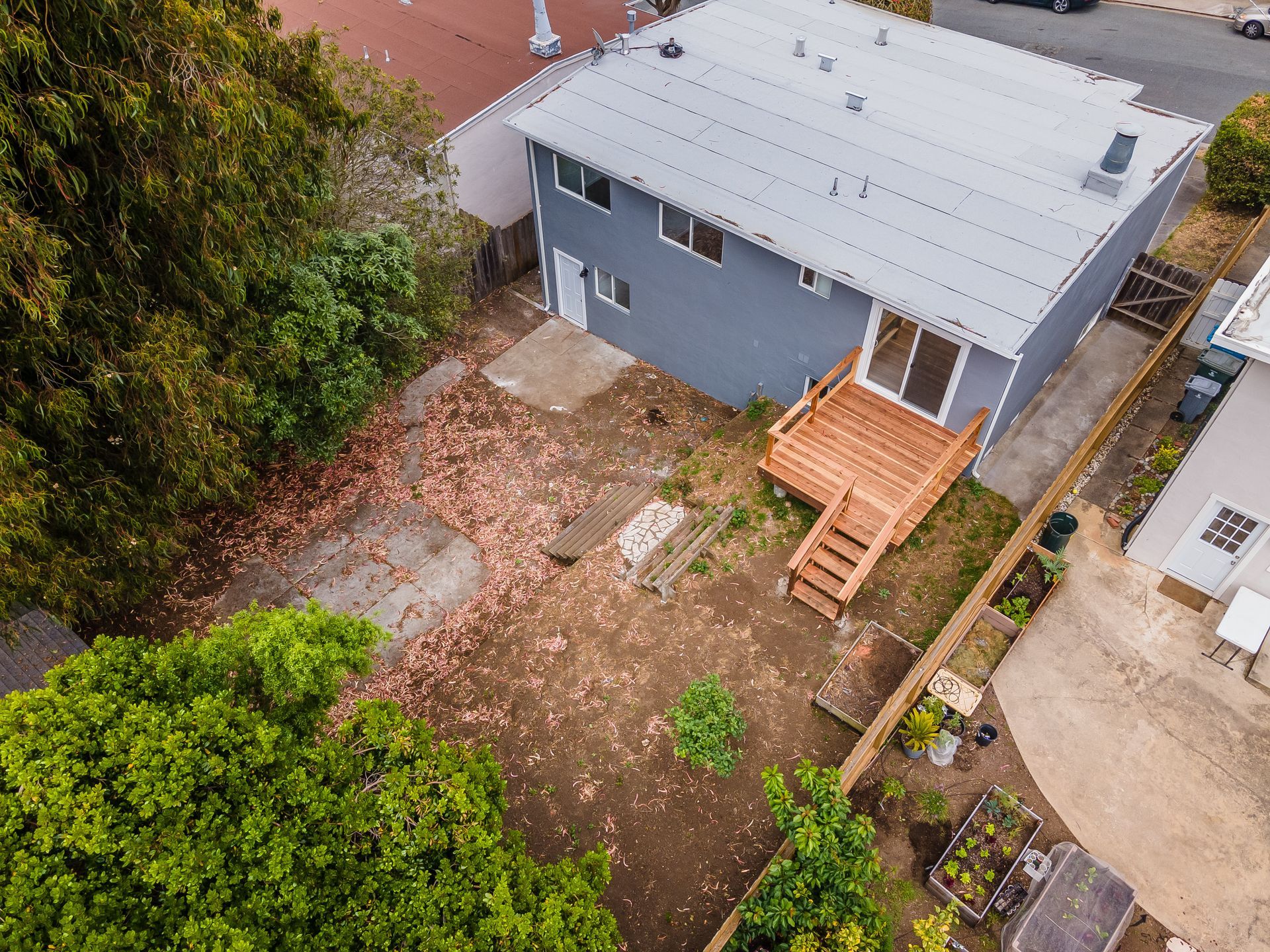 An aerial view of a house with a wooden deck surrounded by trees.