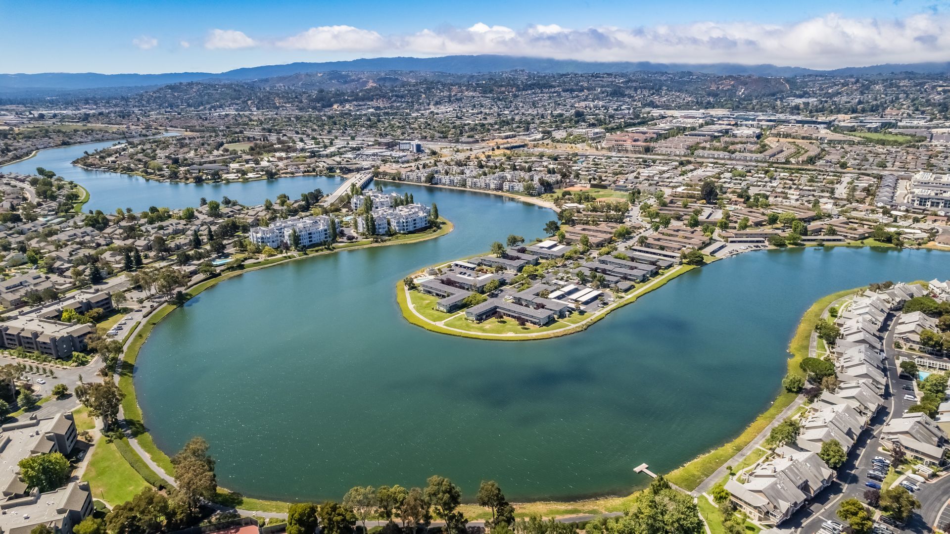 An aerial view of body of water surrounded by houses and trees.