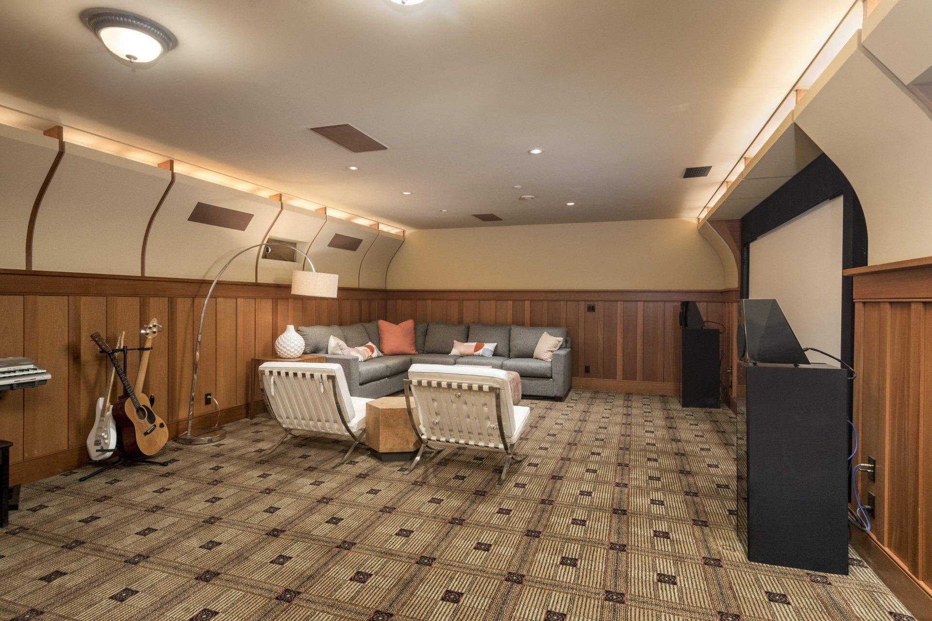 A room with a couch , chairs , a guitar and a piano.