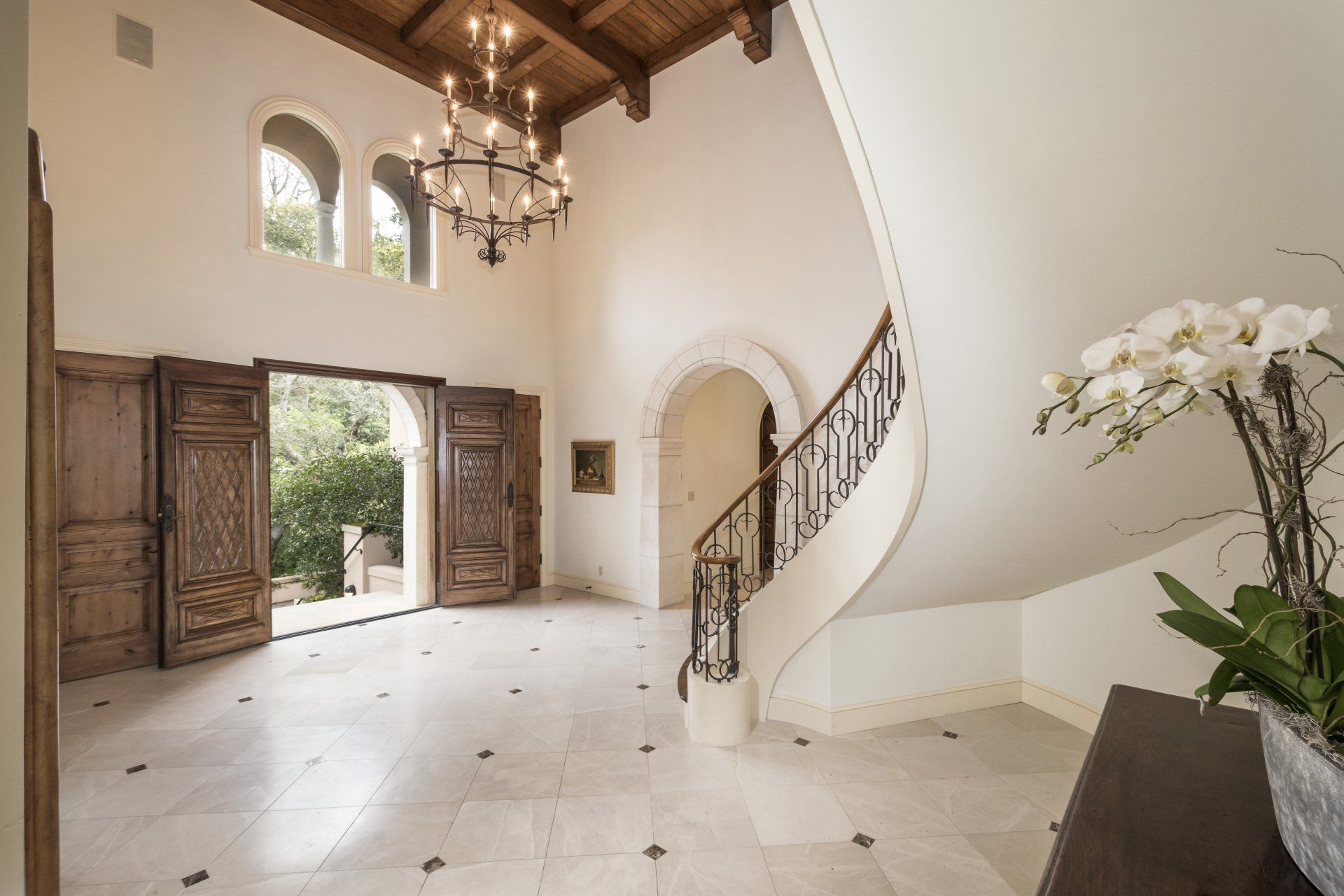An empty hallway with a staircase and a chandelier